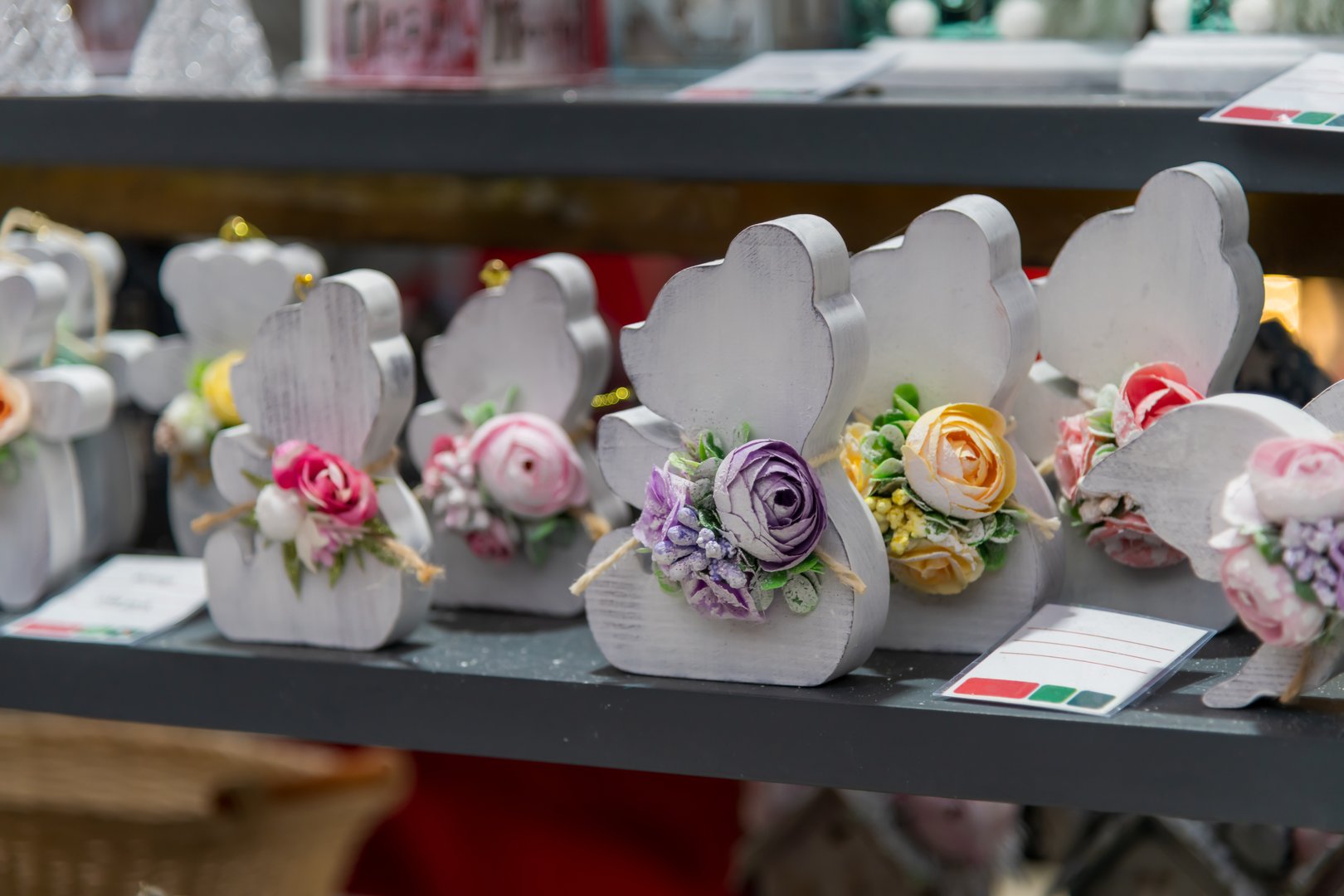 Colorful wooden decorations shaped like animals feature intricate floral designs. These unique pieces catch the eye at a bustling street market, showcasing local craftsmanship and creativity.
