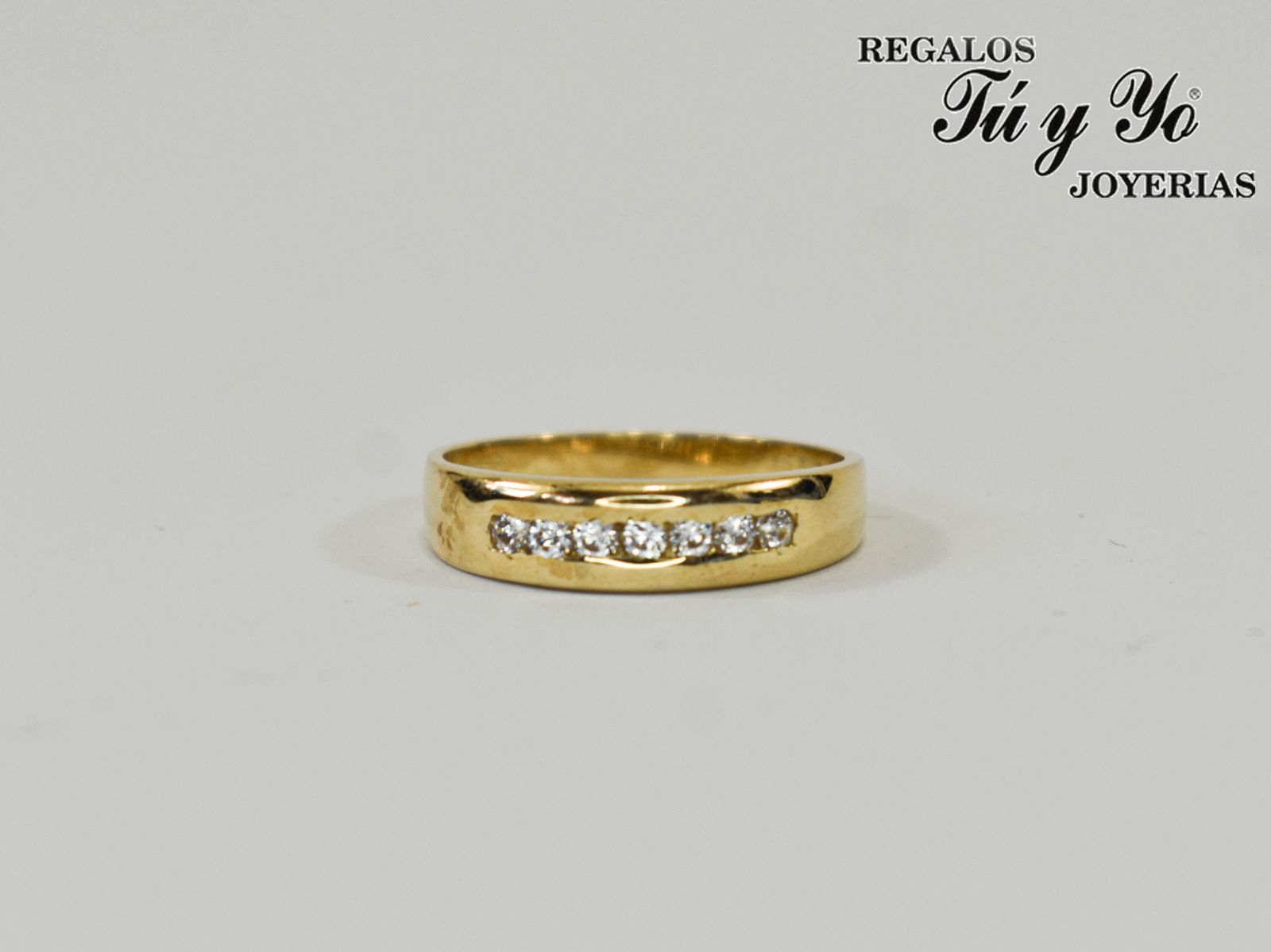 Gold ring with a row of small diamonds, from Regalos Tú y Yo Joyerías, against a plain background.