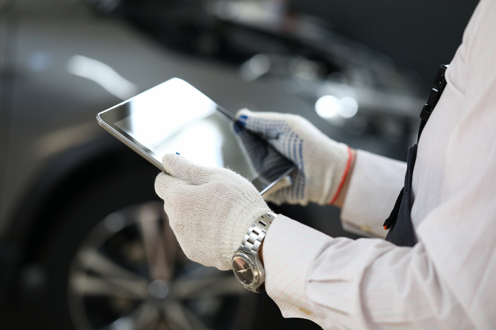 Male master locksmith holds tablet and performs car diagnostics. Apps for car repair concept
