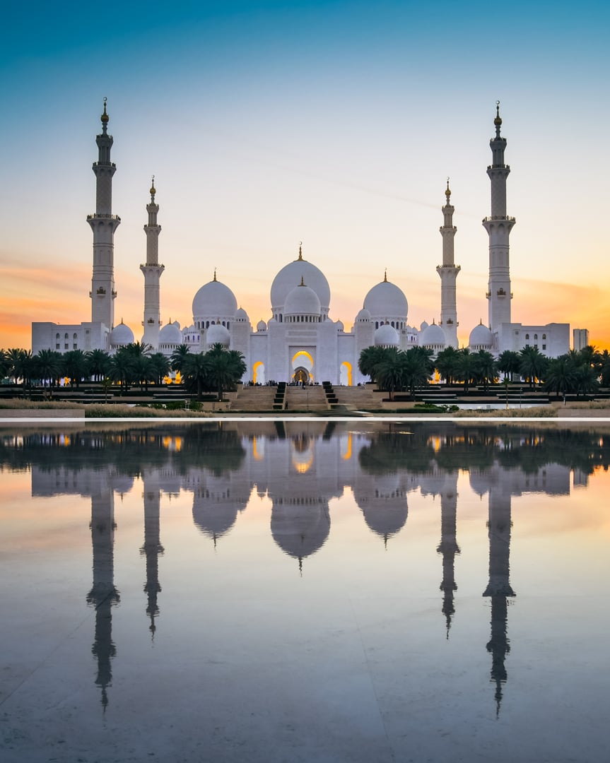 Illuminated Sheikh Zayed Grand Mosque with reflections at sunset, Abu Dhabi, UAE. Tourist sightseeing famous grand mosque attraction in United arab emirates. 4k high quality colorful day to night