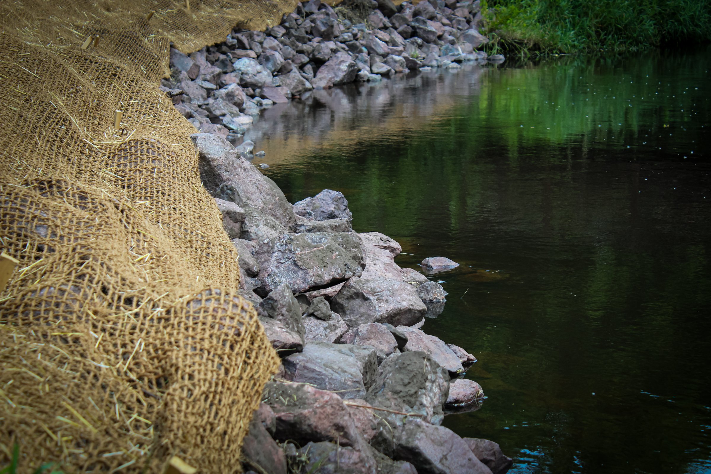 a bank stabilization project along a beautiful creek. watershed restoration with riprap and an erosion control blanket.