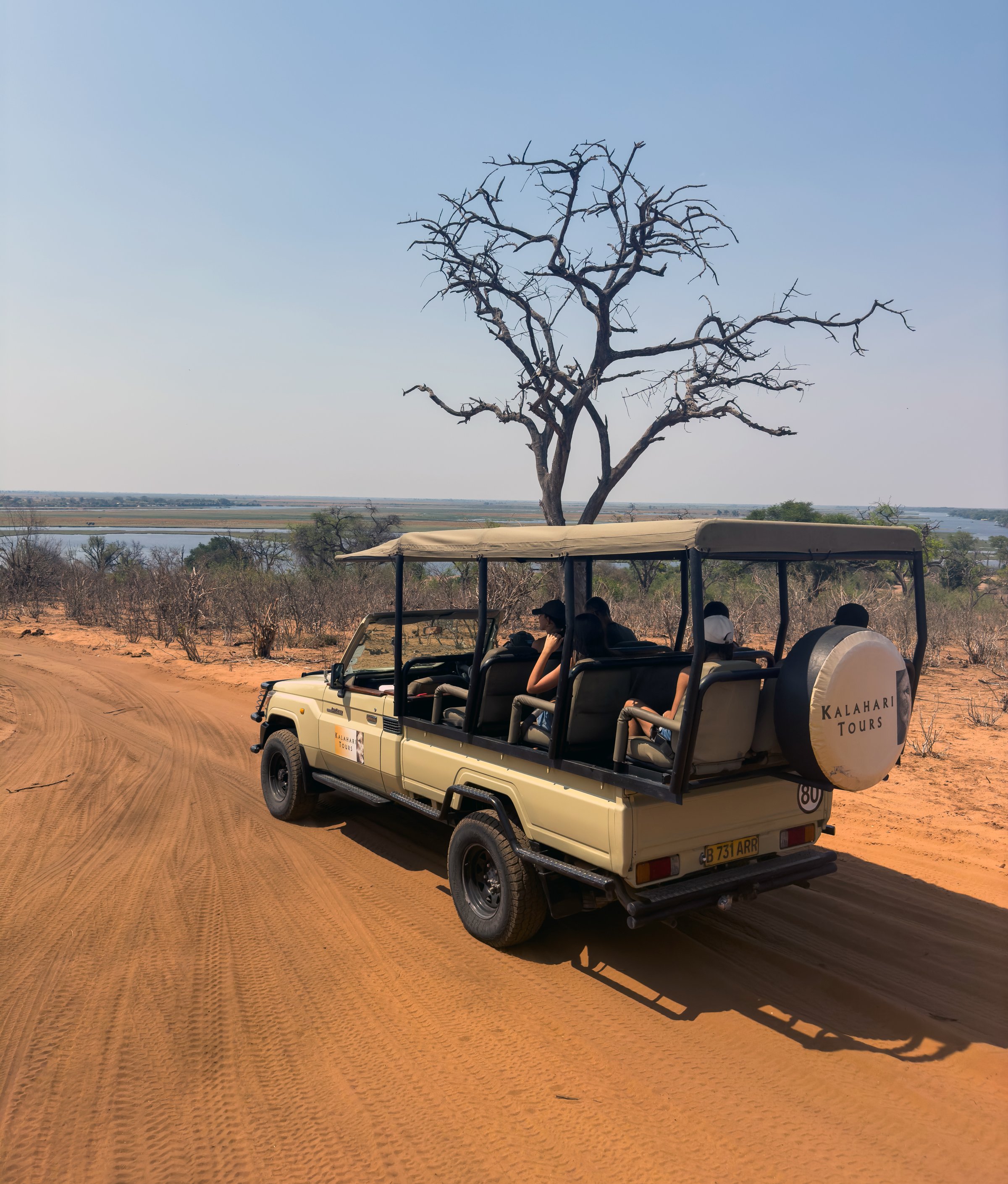 A safari jeep on a dirt road in the African savannah.