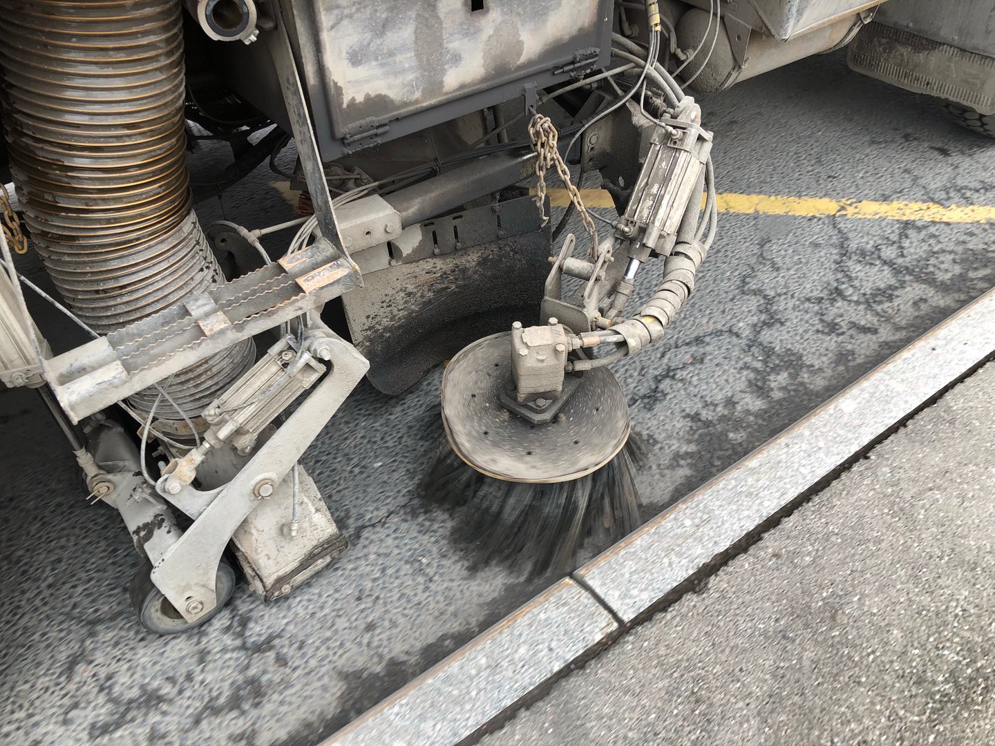 Road vacuum cleaner with brush at the curb on the road at work