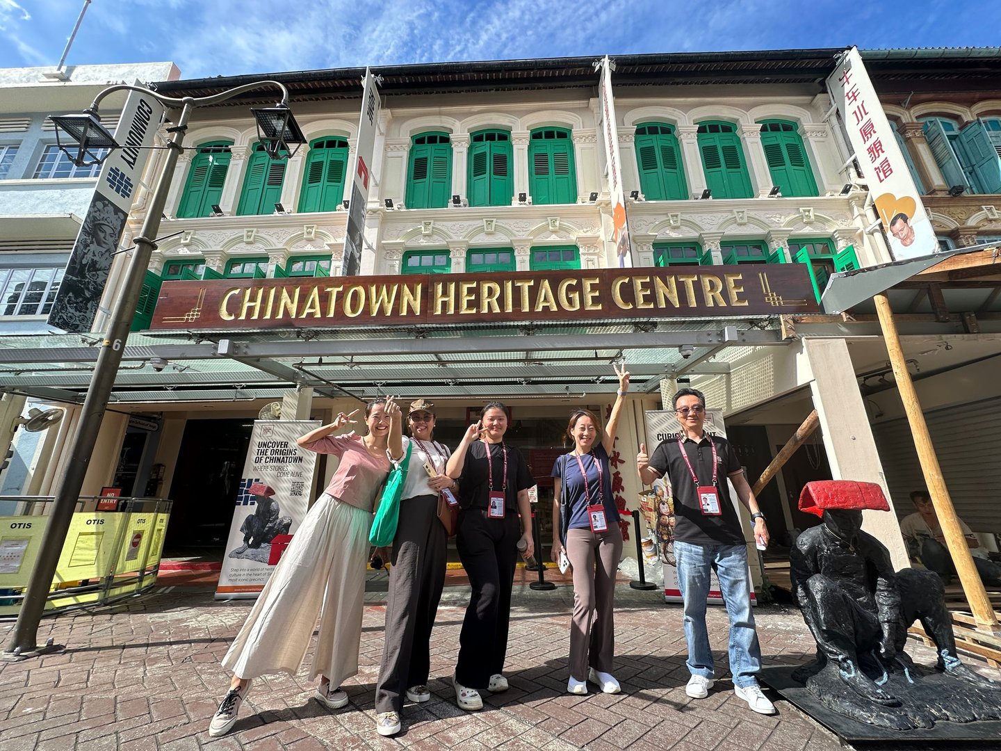 Group of people posing in front of Chinatown Heritage Centre, Singapore, under a clear blue sky.