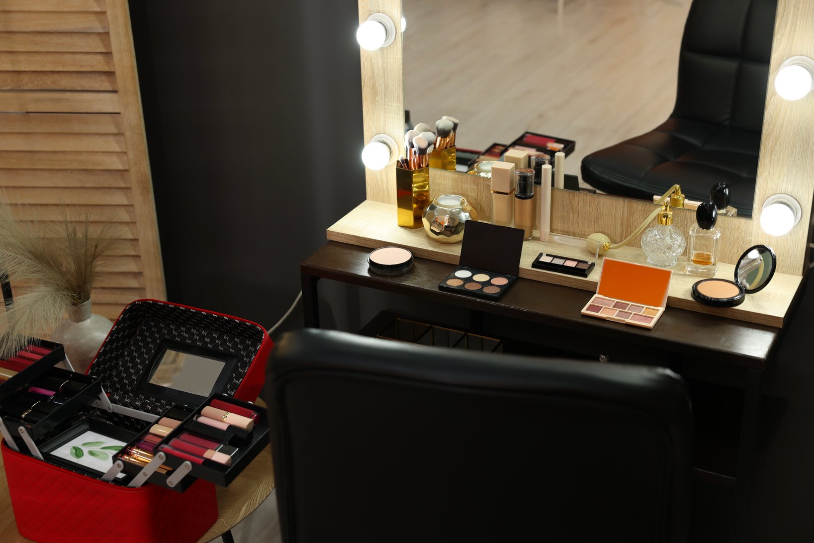 Makeup room. Stylish mirror near dressing table with beauty products and chair indoors