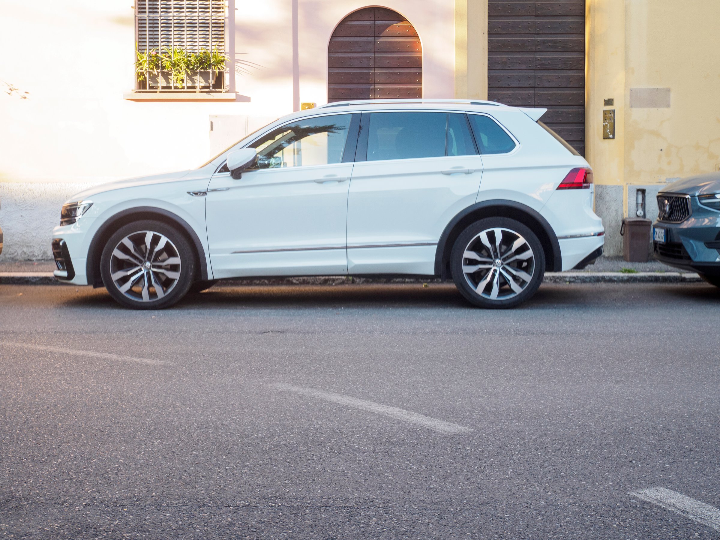 Cremona, Italy August 4th 2025 White Volkswagen Tiguan R Line parked beside suburban homes, highlighting sporty styling and premium alloy wheel design
