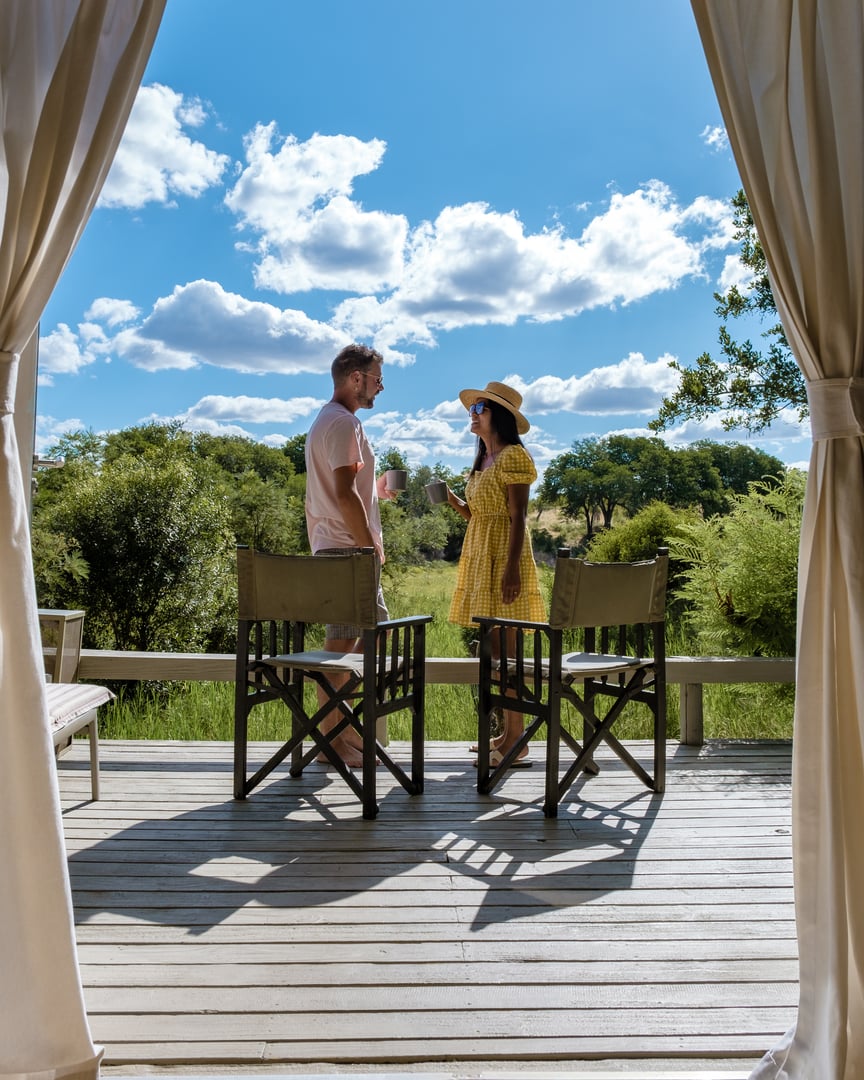 couple men and woman in front of an safari tent on luxury safari, South Africa, a luxury safari lodge in the bush of a Game reserve