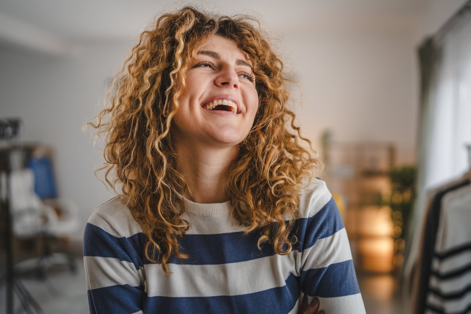 Portrait of adult caucasian woman with curly hair at home happy smile