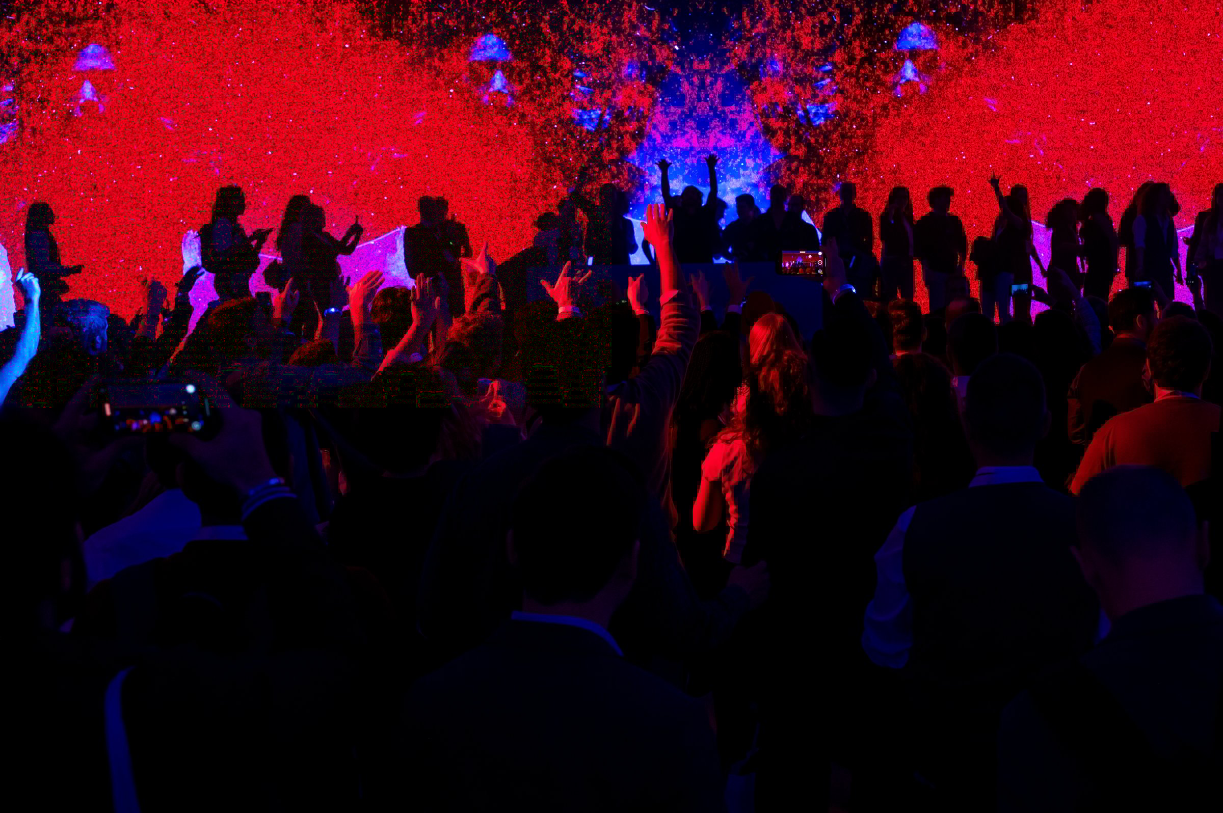 Crowd partying and raising hands at concert while dj performing on stage