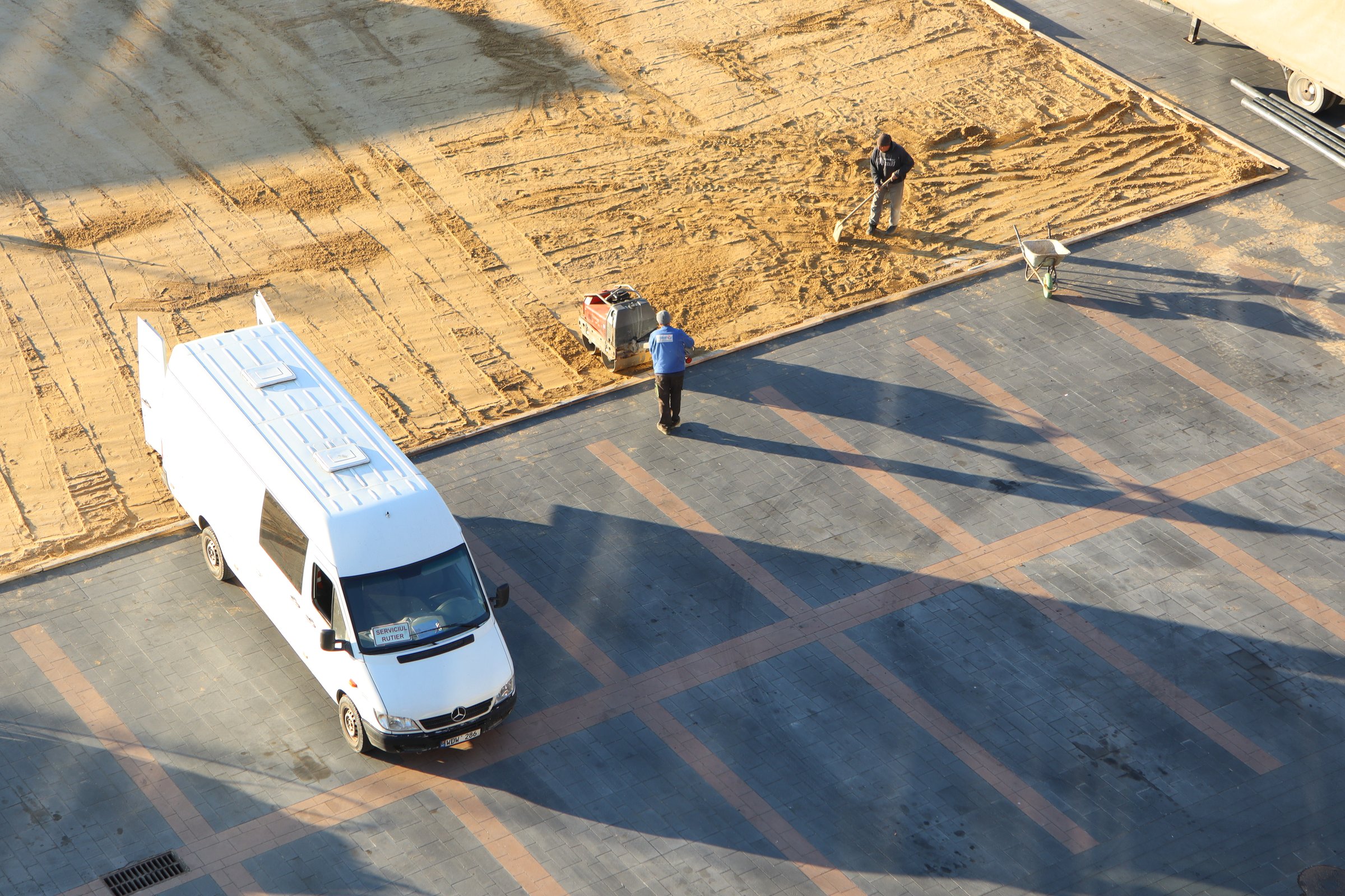 Several workers are actively engaged in site preparation activities adjacent to a parked van on a construction site