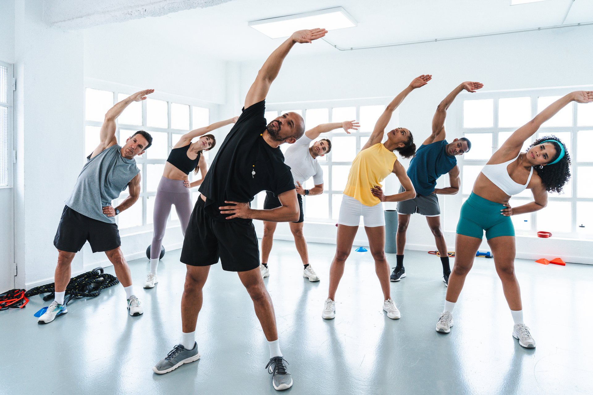 Multiethnic group of sportive people doing functional workout in training class gym diverse athletes stretching together in a bright. Spacious gym. Preparing for a functional training workout