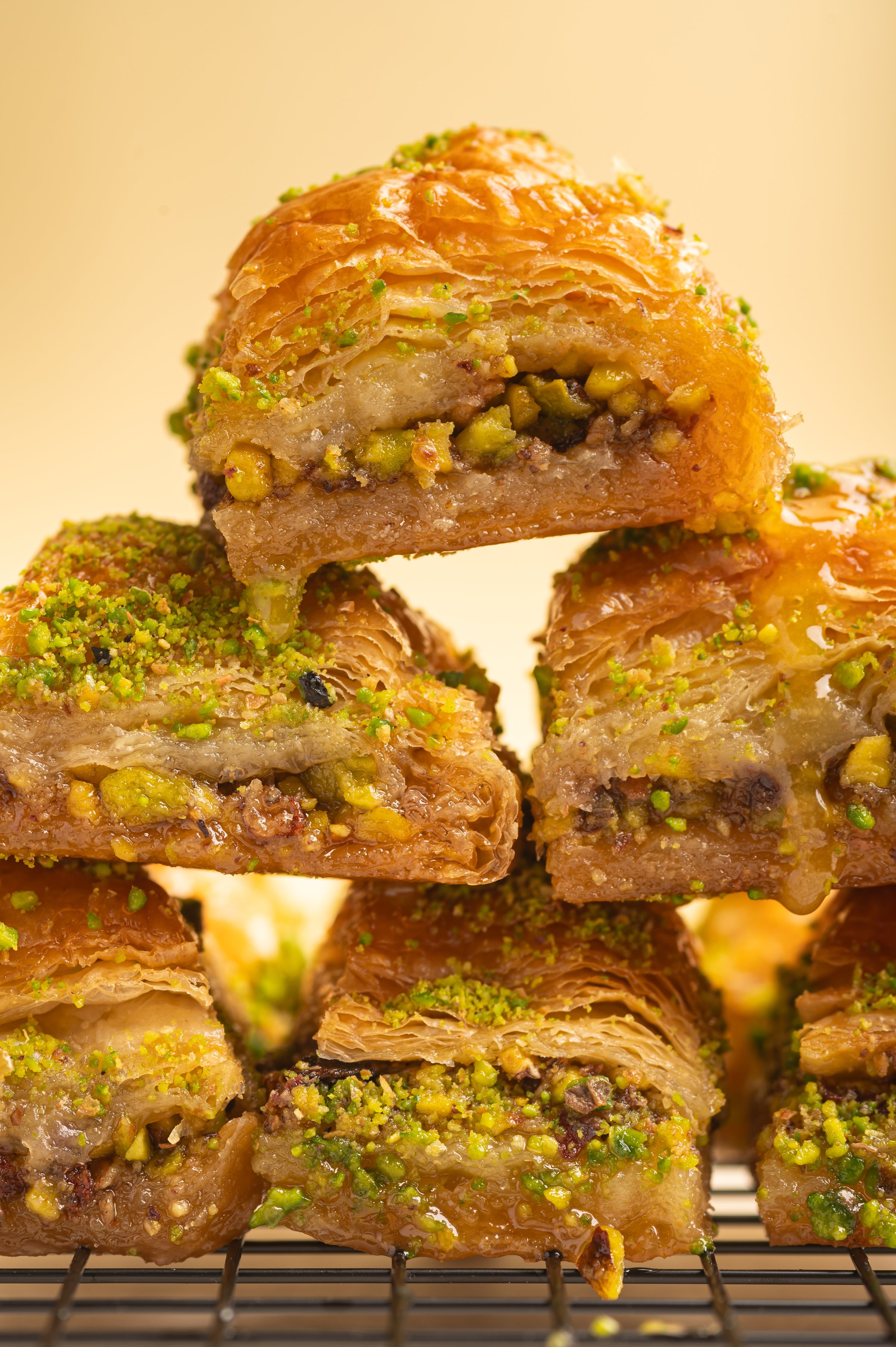 Flaky baklava topped with finely ground pistachios. The rich texture of syrup-soaked phyllo dough and vibrant green nuts highlights the indulgent nature of this iconic Middle Eastern dessert