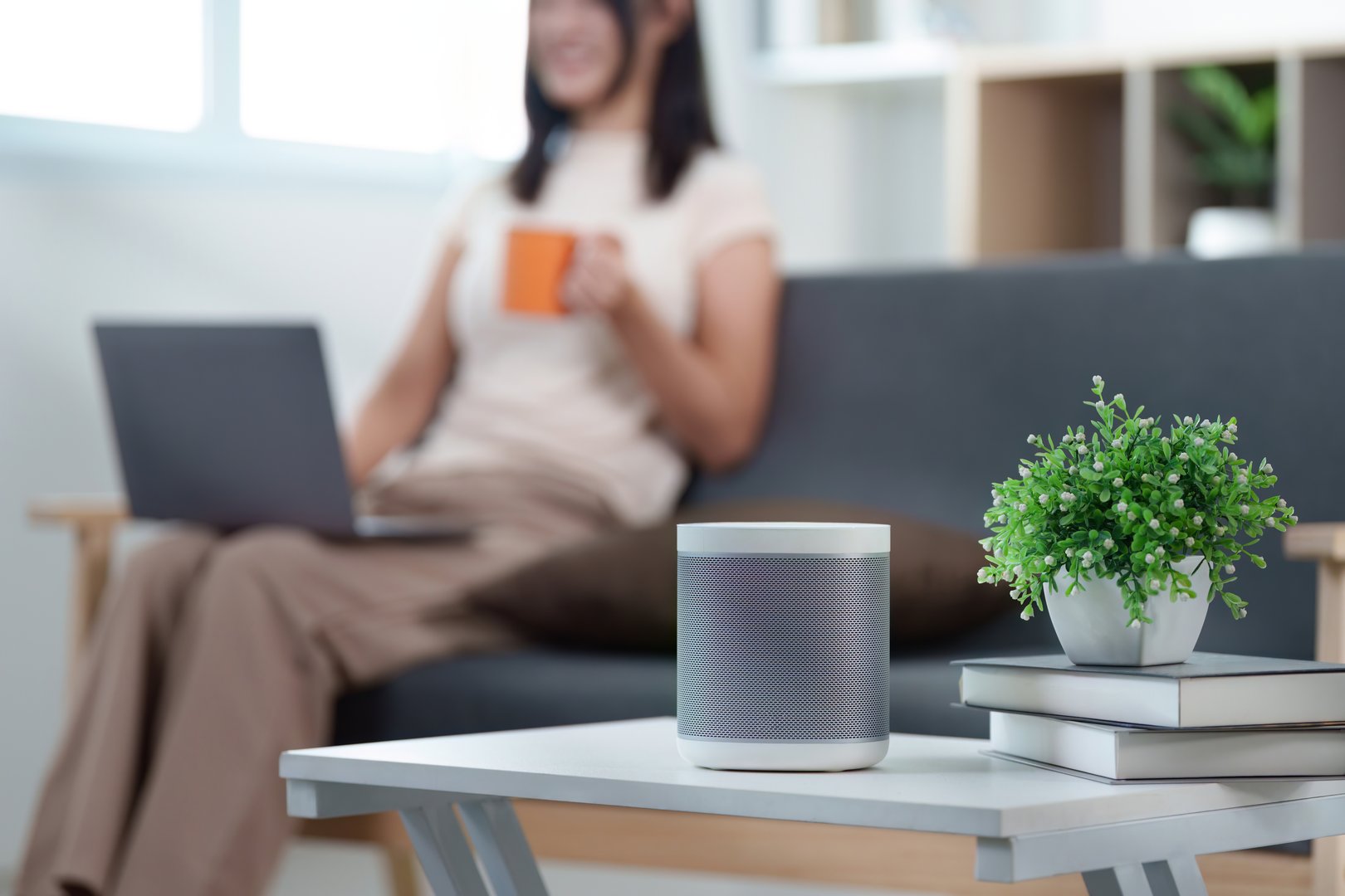 A woman relaxes with a cup of coffee and a laptop, showcasing the integration of smart technology in a comfortable living environment.