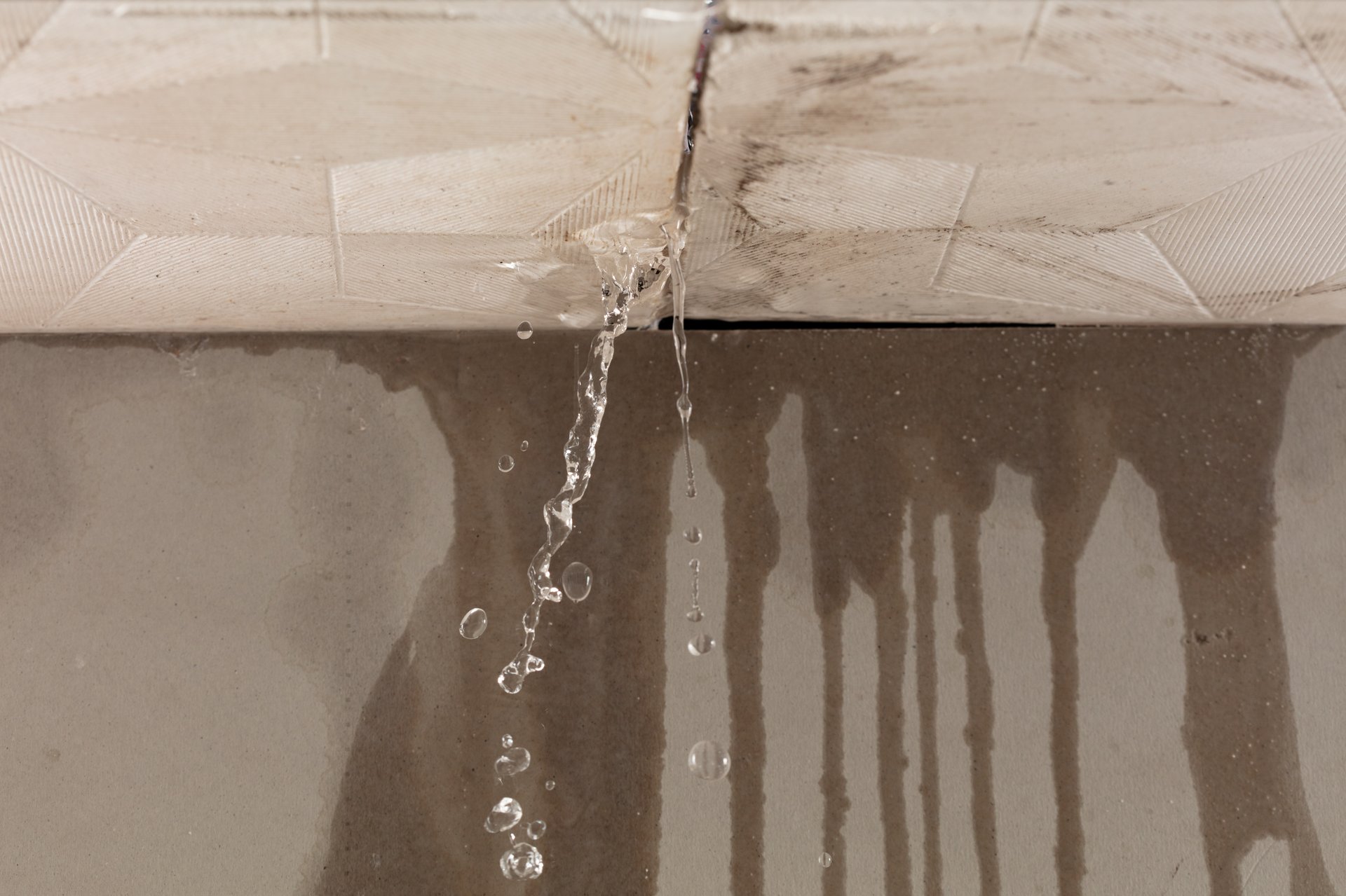 Heavy storm rain create water flow from edge of ceiling and dirty stain on wall. Water leaking from top ceiling as droplets and flow in old house