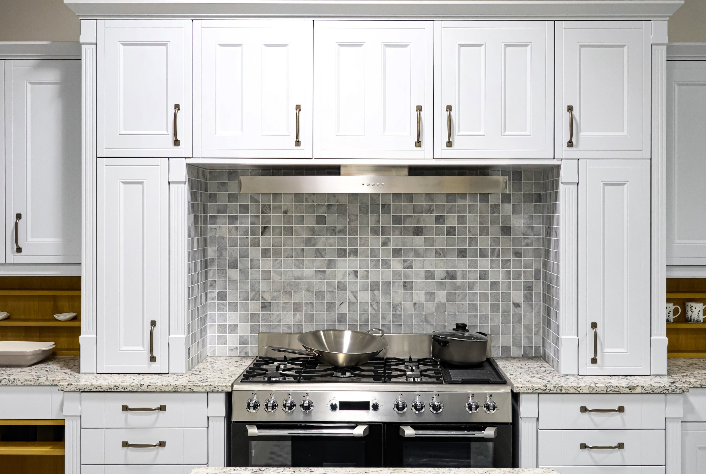 Contemporary kitchen design with white cabinetry, granite countertops, stone tile backsplash, and stainless steel appliances