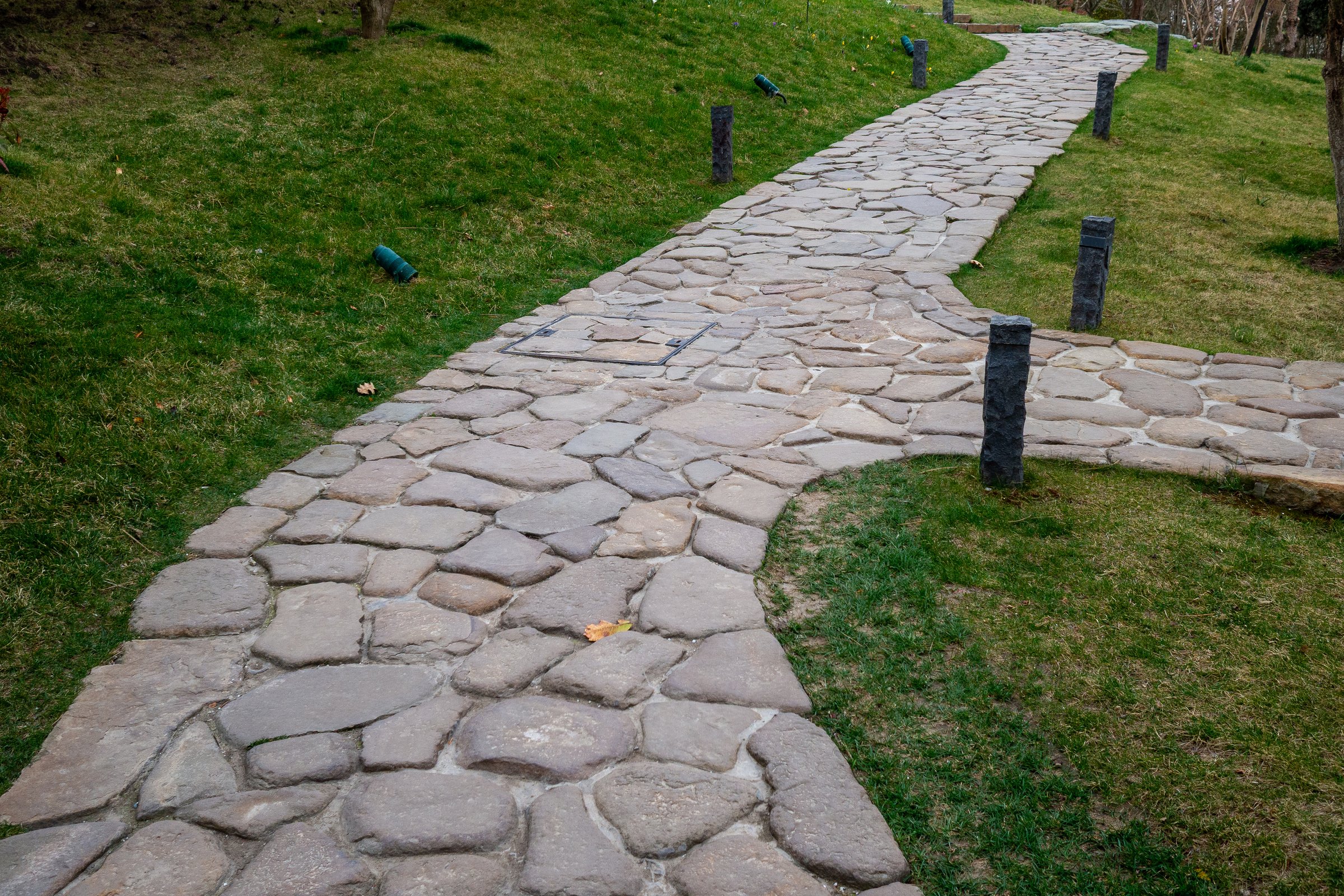 Natural stone walkway winds through lawn with small lighting posts. Good for sustainability and outdoor landscaping imagery.