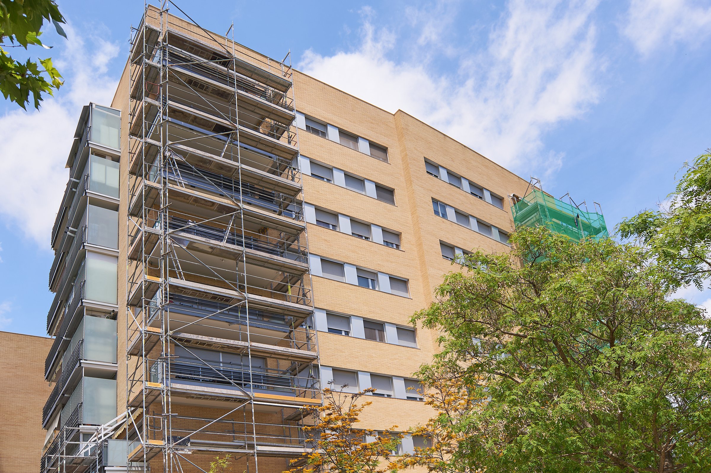 Scaffolding on a building under construction with yellow insulation. Urban setting with clear sky