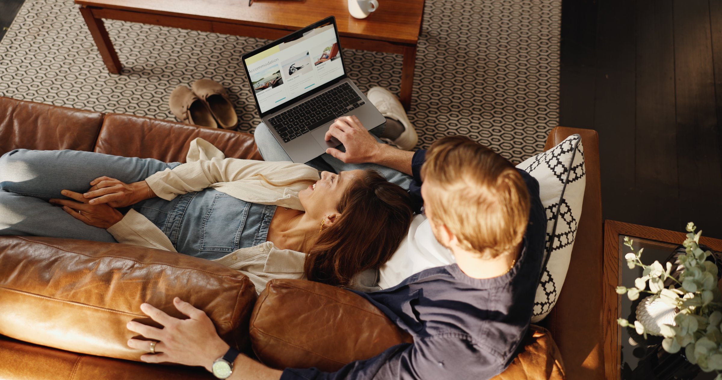 Laptop, relax and top view of couple in home to search for deal on accommodation or hotel booking. Above, holiday or people on couch together for bonding, travel options or resort homepage for review