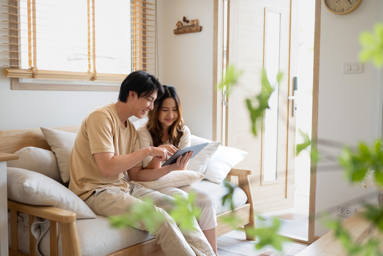 Relaxed asian couple using a digital tablet while relaxing together on sofa at home..