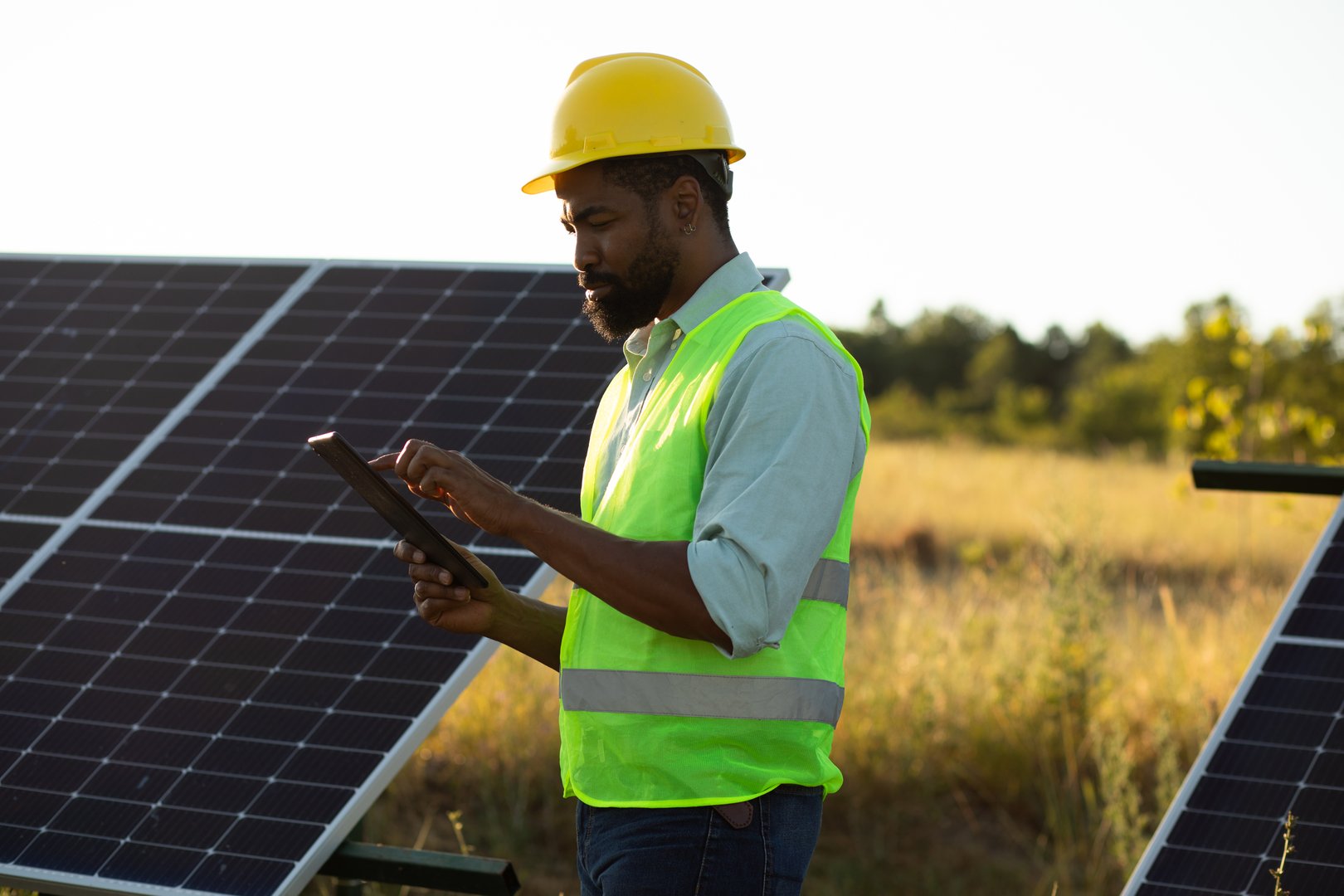 Engineer using digital tablet while inspecting solar panels in field