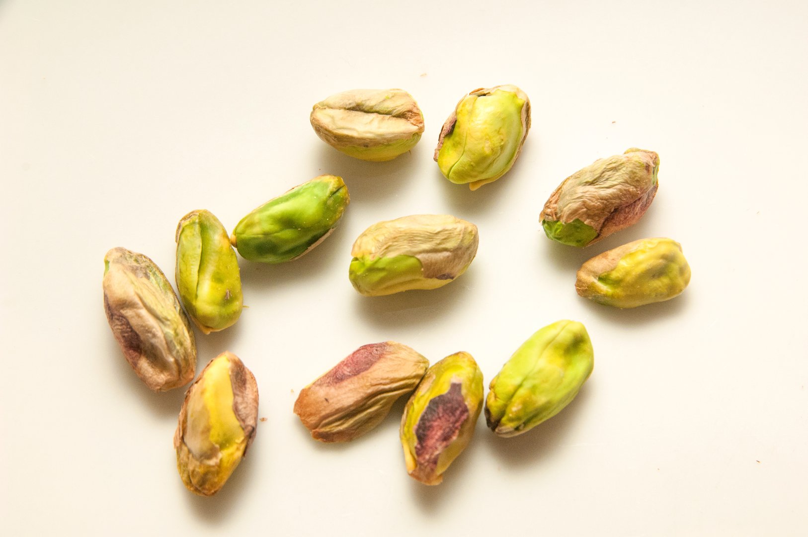 Shelled and unshelled pistachios on white background,and hands holding some pistachios