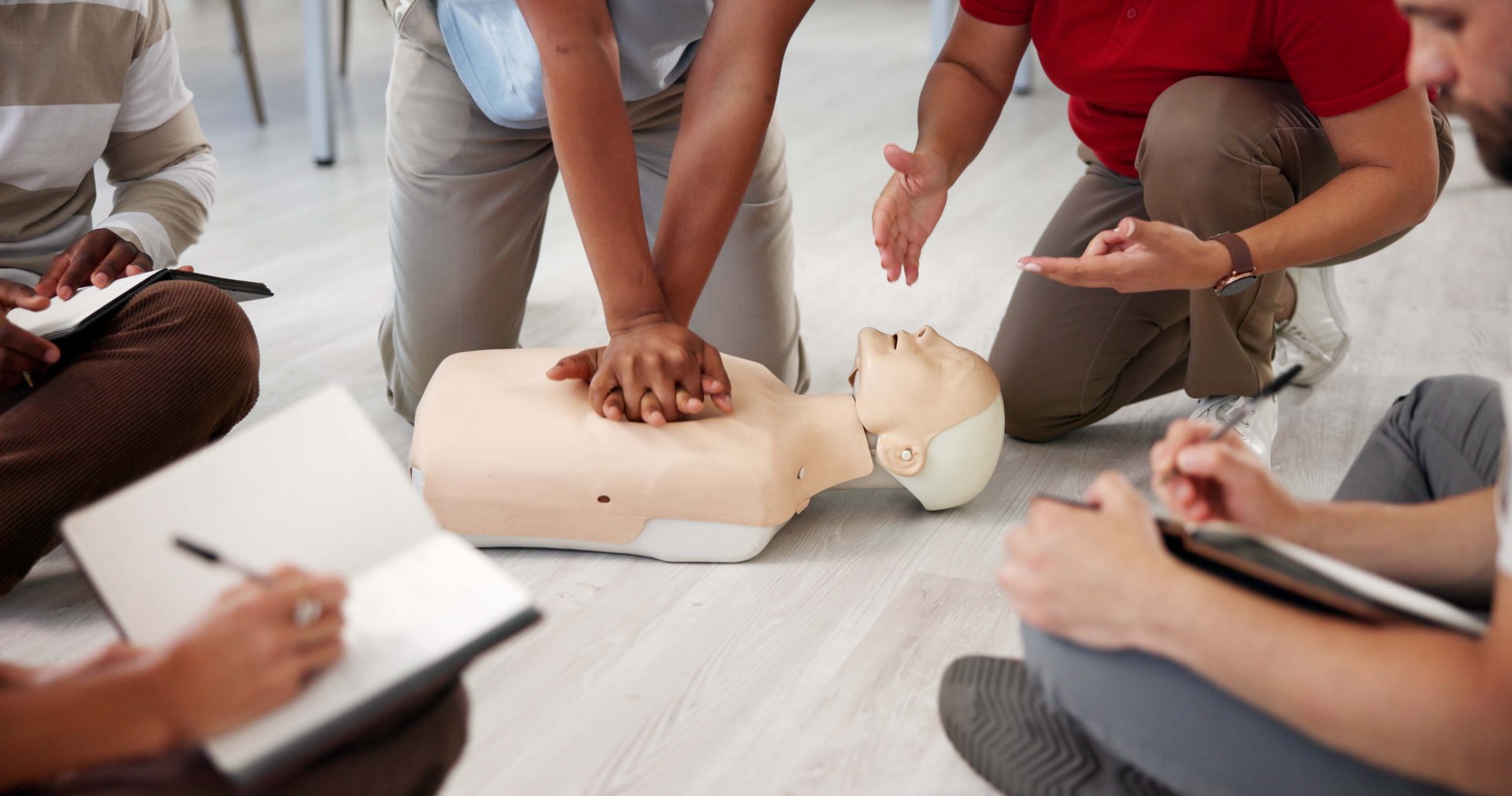 People, mannequin or hands in office for CPR, first aid workshop or chest compression lesson. Colleagues, emergency practice or dummy in agency for life saving procedure, notes or employee engagement