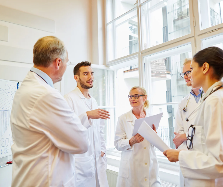 Group of medical professionals in white lab coats having a discussion in a bright room.