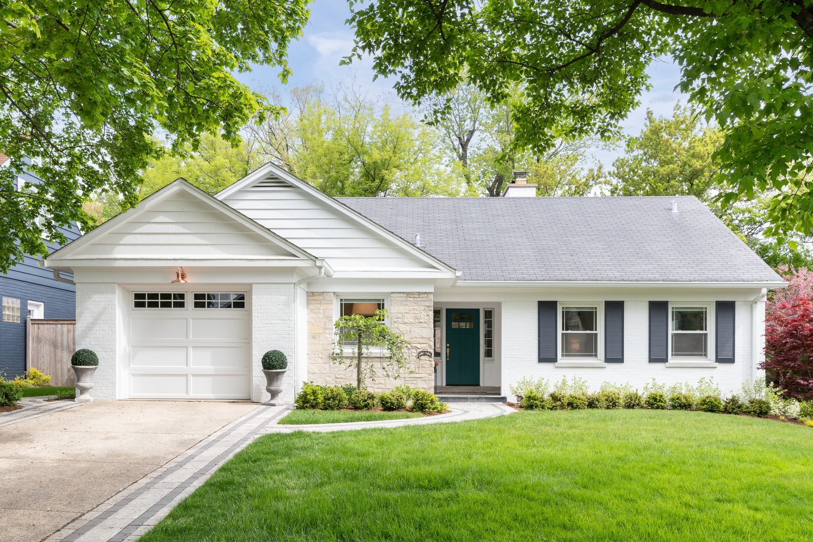 Elmhurst, IL, USA - April 28, 2023: A beautiful suburban home with a white brick and stone siding, beautiful landscaping, and a rose gold light over the garage.