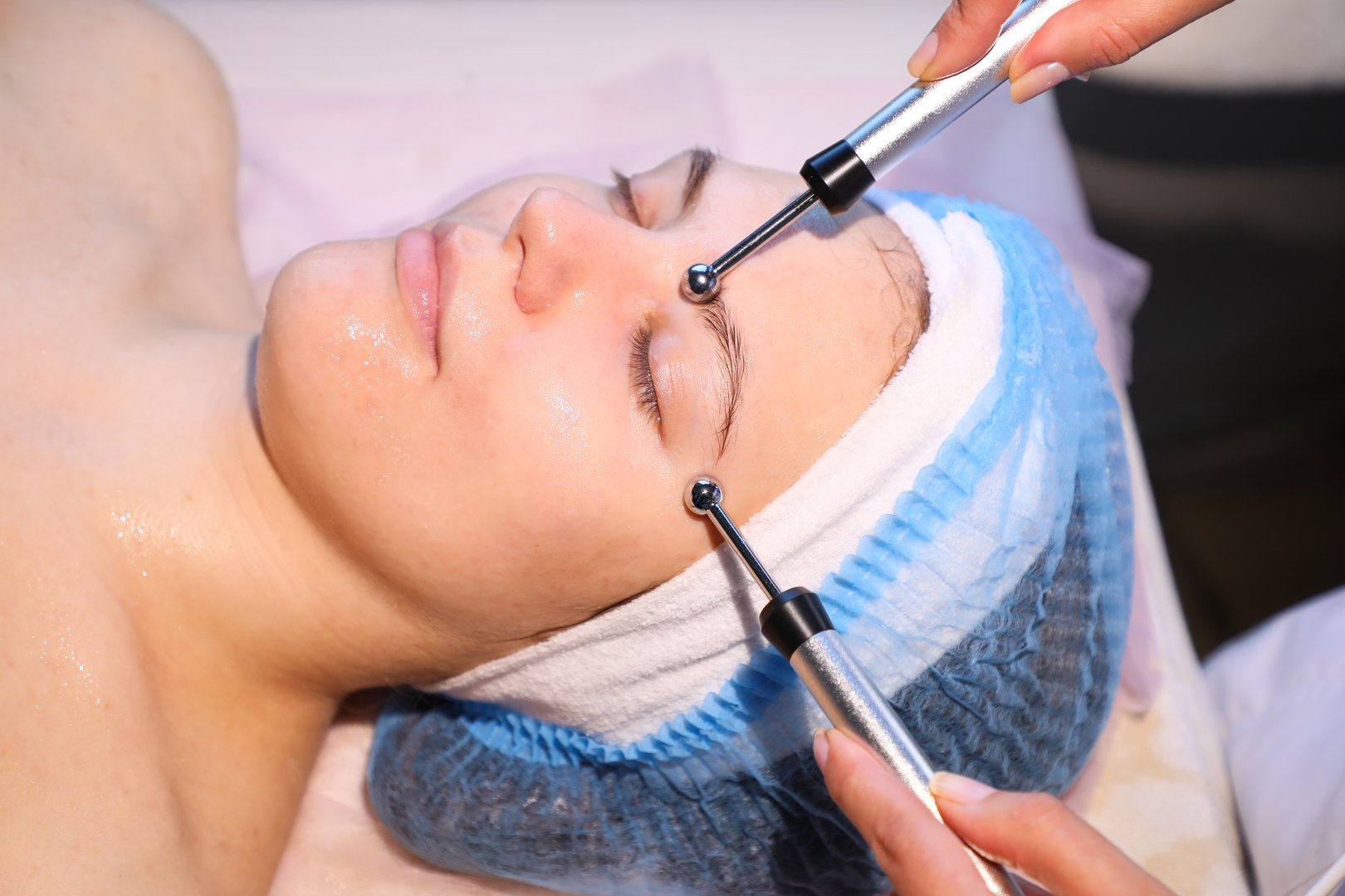 Modern Microcurrent therapy on the face of a young woman is performed by an experienced cosmetologist (from the series cosmetology room).
