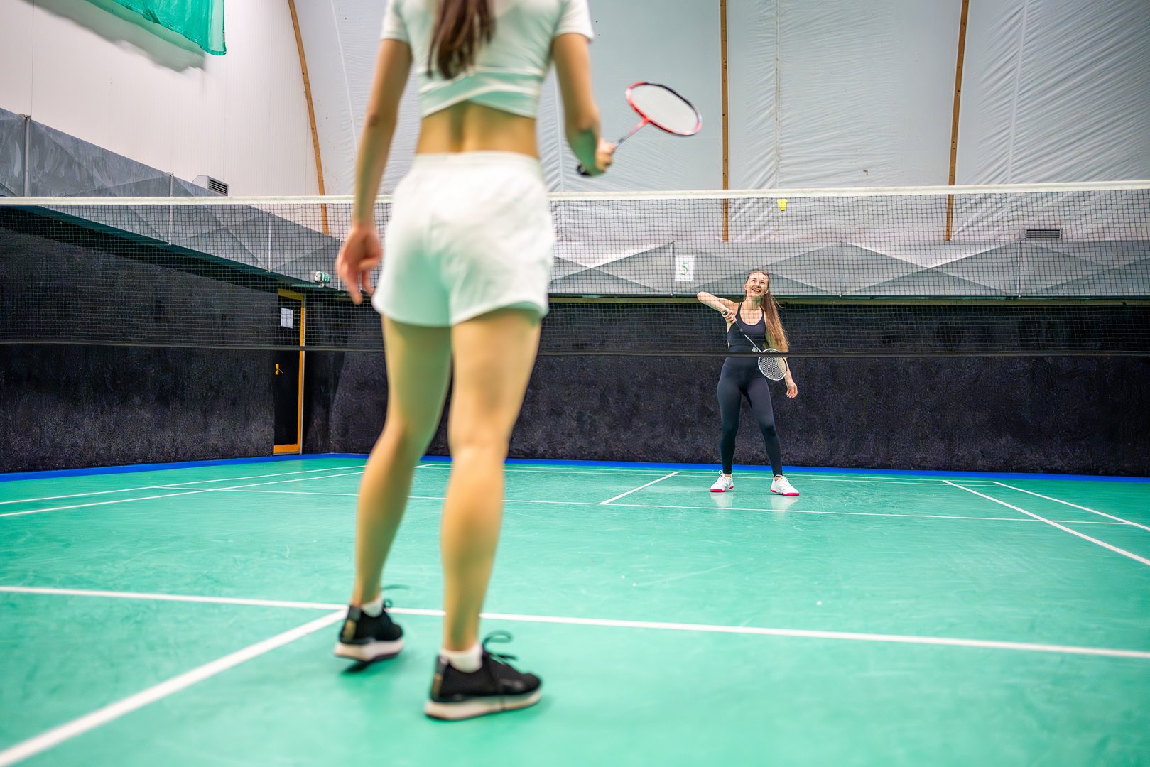 Sports young women with racket and shuttlecock is exercising, playing in badminton on inside court. High quality photo