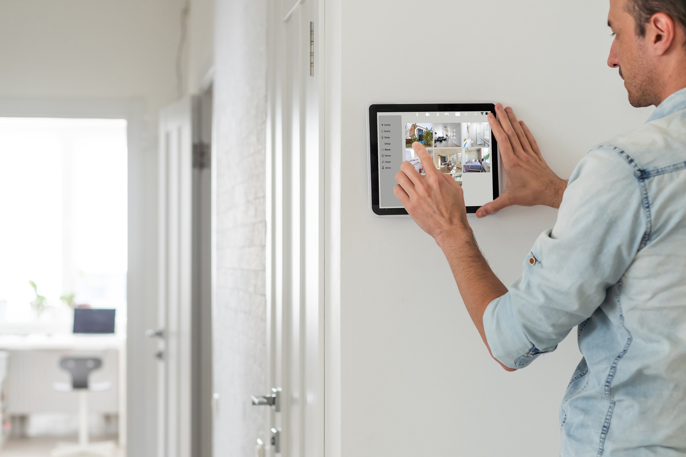 man using tablet panel application for control smart home living. Blonde female touch Wireless device controller for home automation on the wall. High quality photo