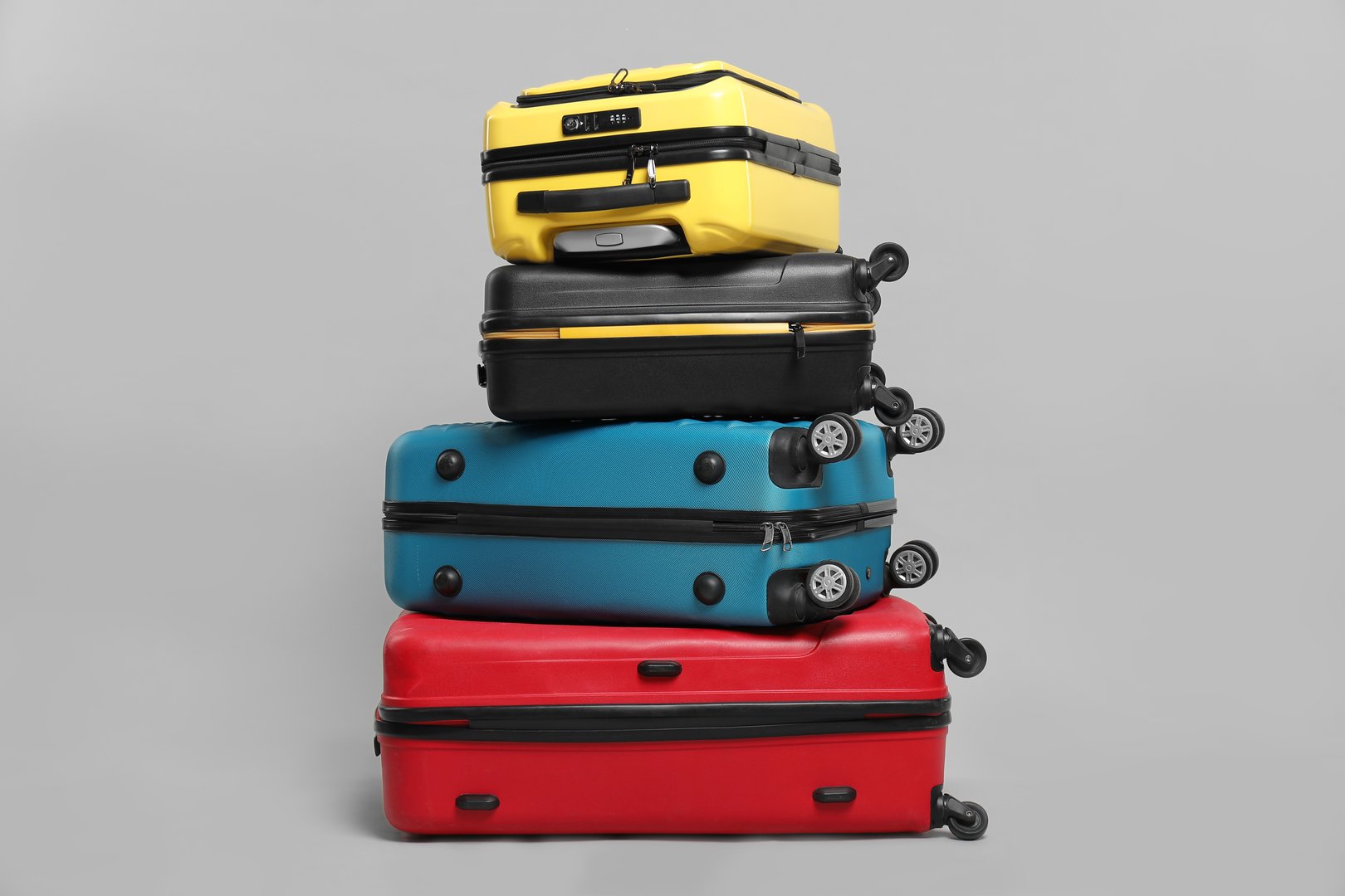 Stack of colorful suitcases on grey background