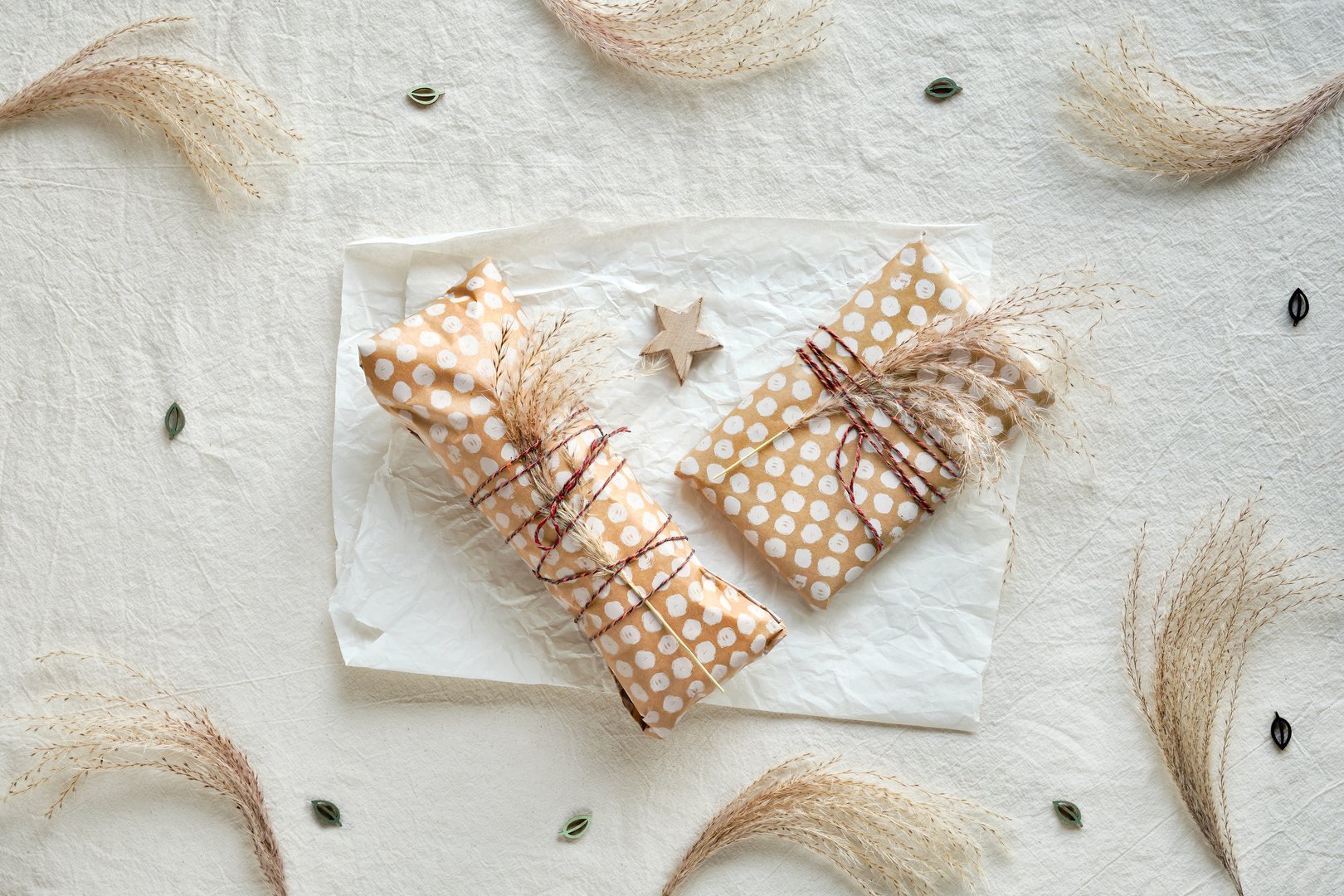 Regalos artesanales envueltos en papel kraft beige con hierba seca atada con cordón de algodón