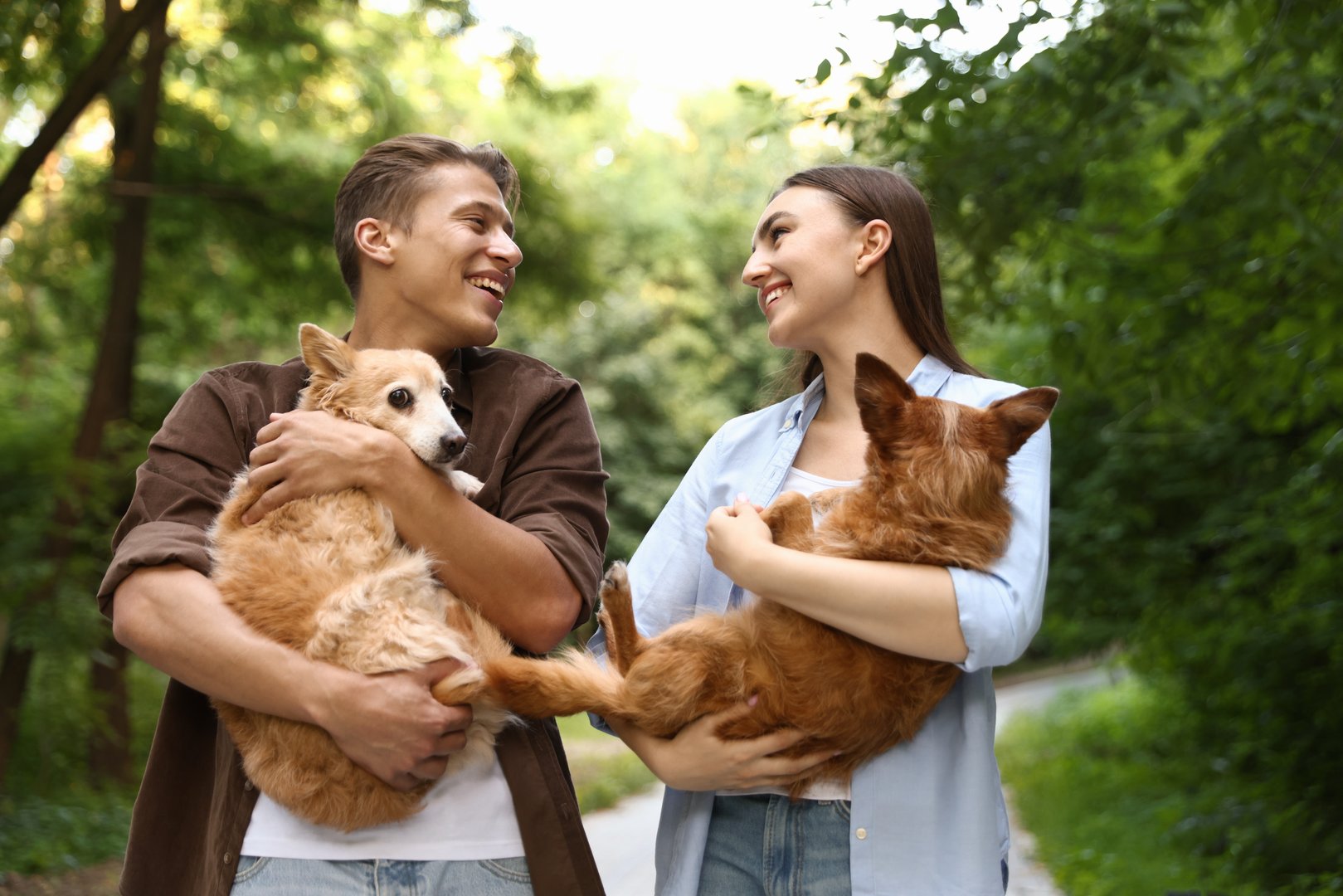 Happy couple holding their cute dogs outdoors
