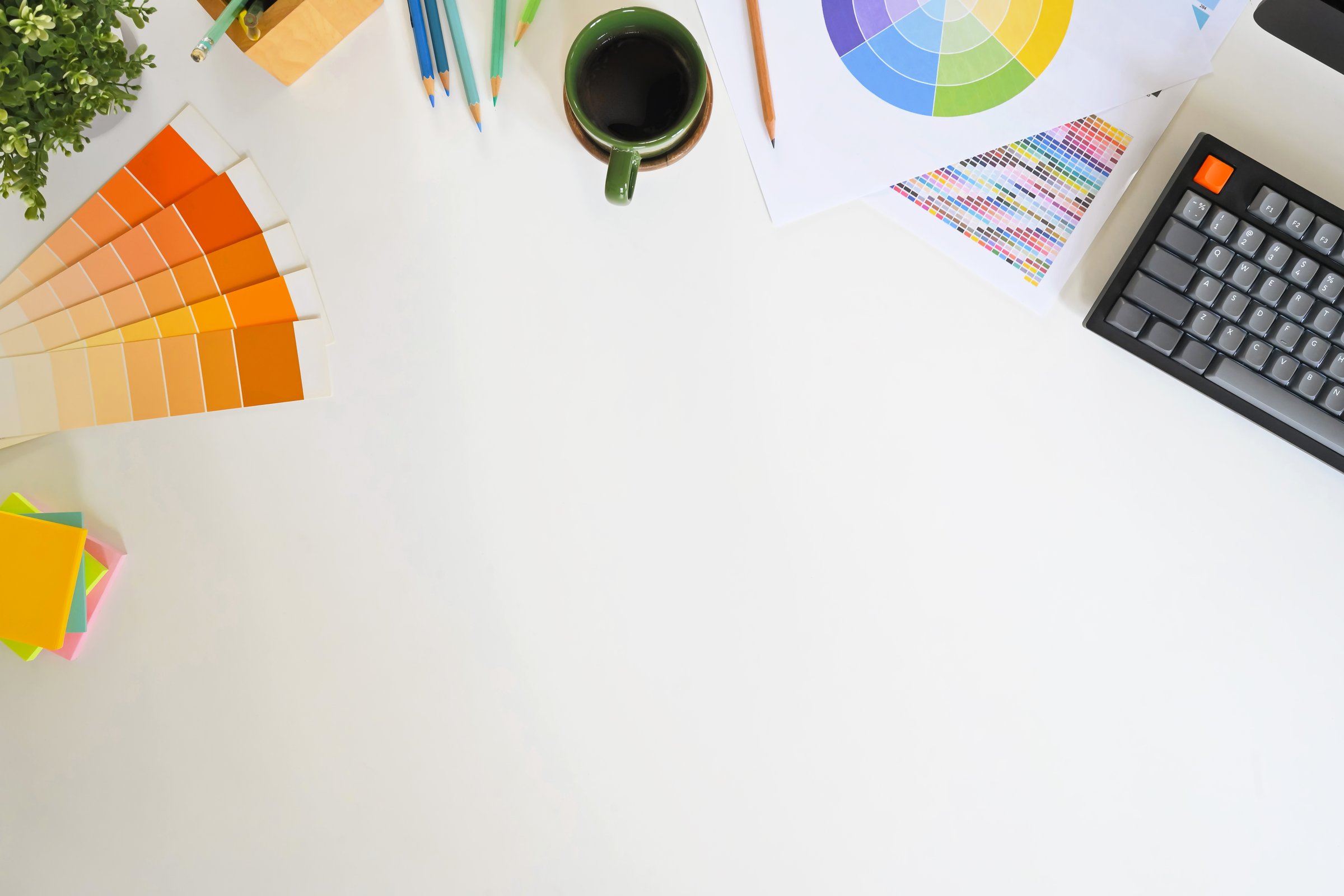 Top view of creative designer workspace with color palette, and coffee cup on white desk.