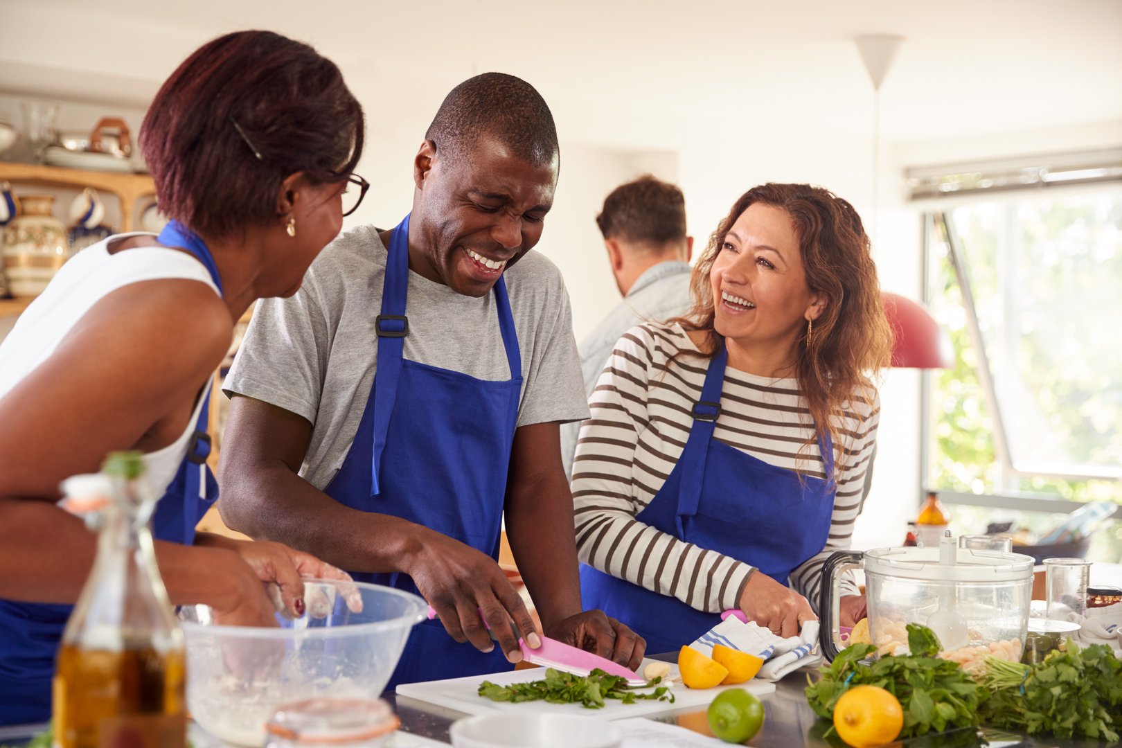 Male And Female Adult Students Preparing Ingredients For Dish In Kitchen Cookery Class
