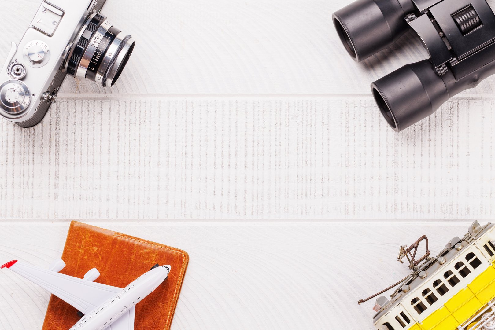 Travel-themed flat lay with camera, toy airplane, and tram, arranged creatively on table with copy space for your ideas
