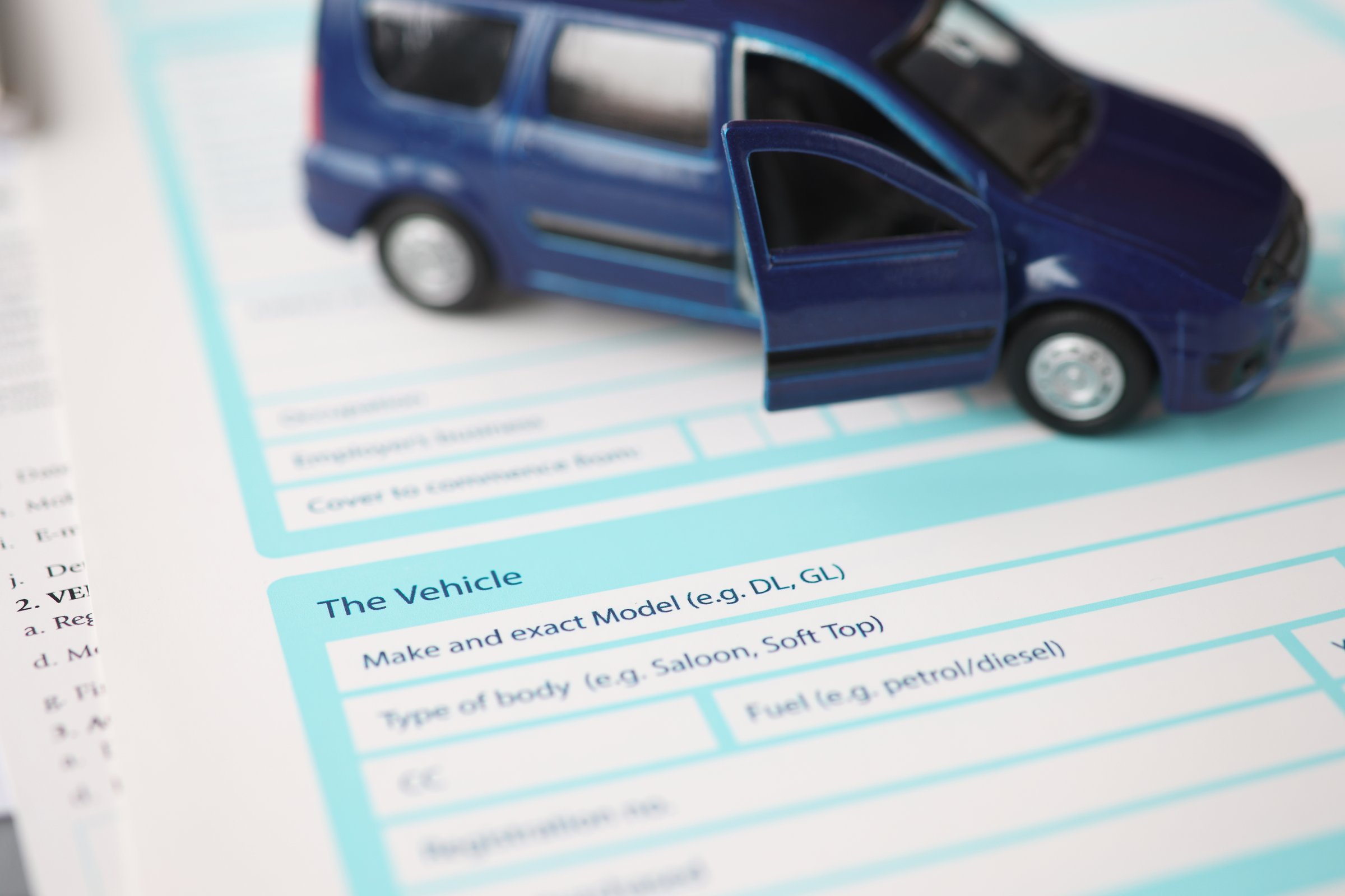 Blue toy car standing on insurance document closeup. Types of car insurance concept