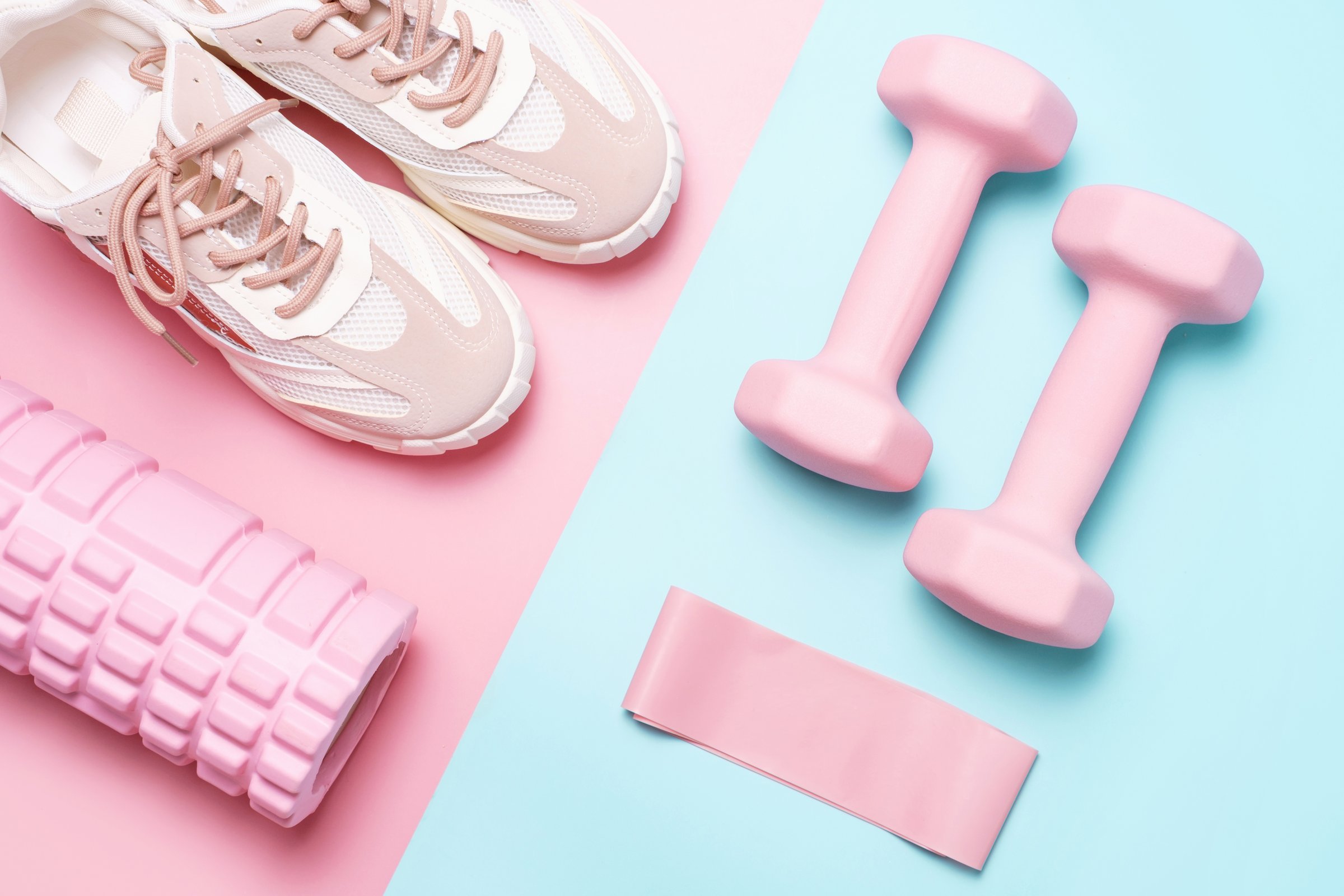 Set of sports accessories on pink and blue background close up top view.