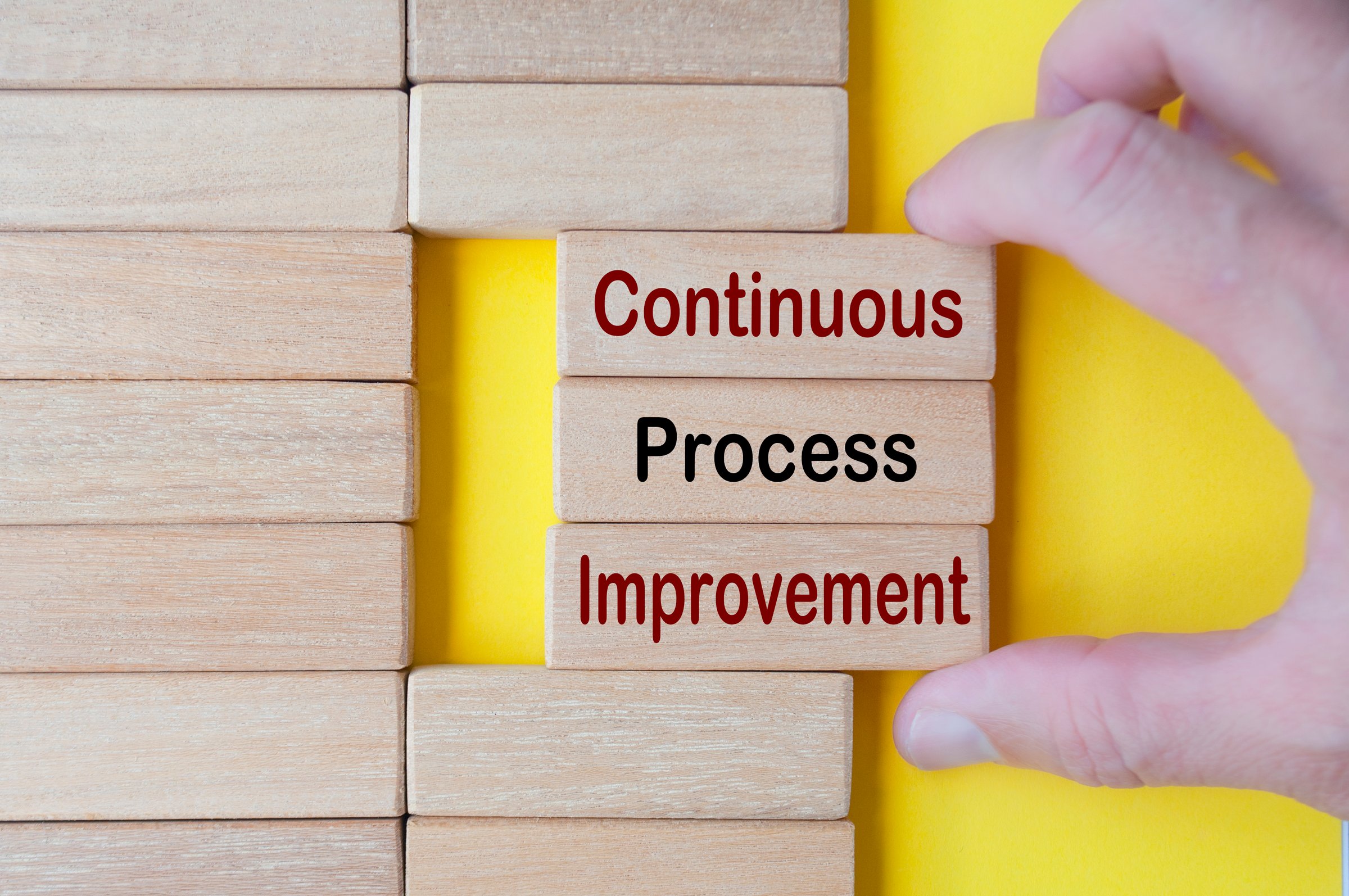 Hand pulling wooden blocks with continuous process improvement text. Business culture and Operational excellence concept.
