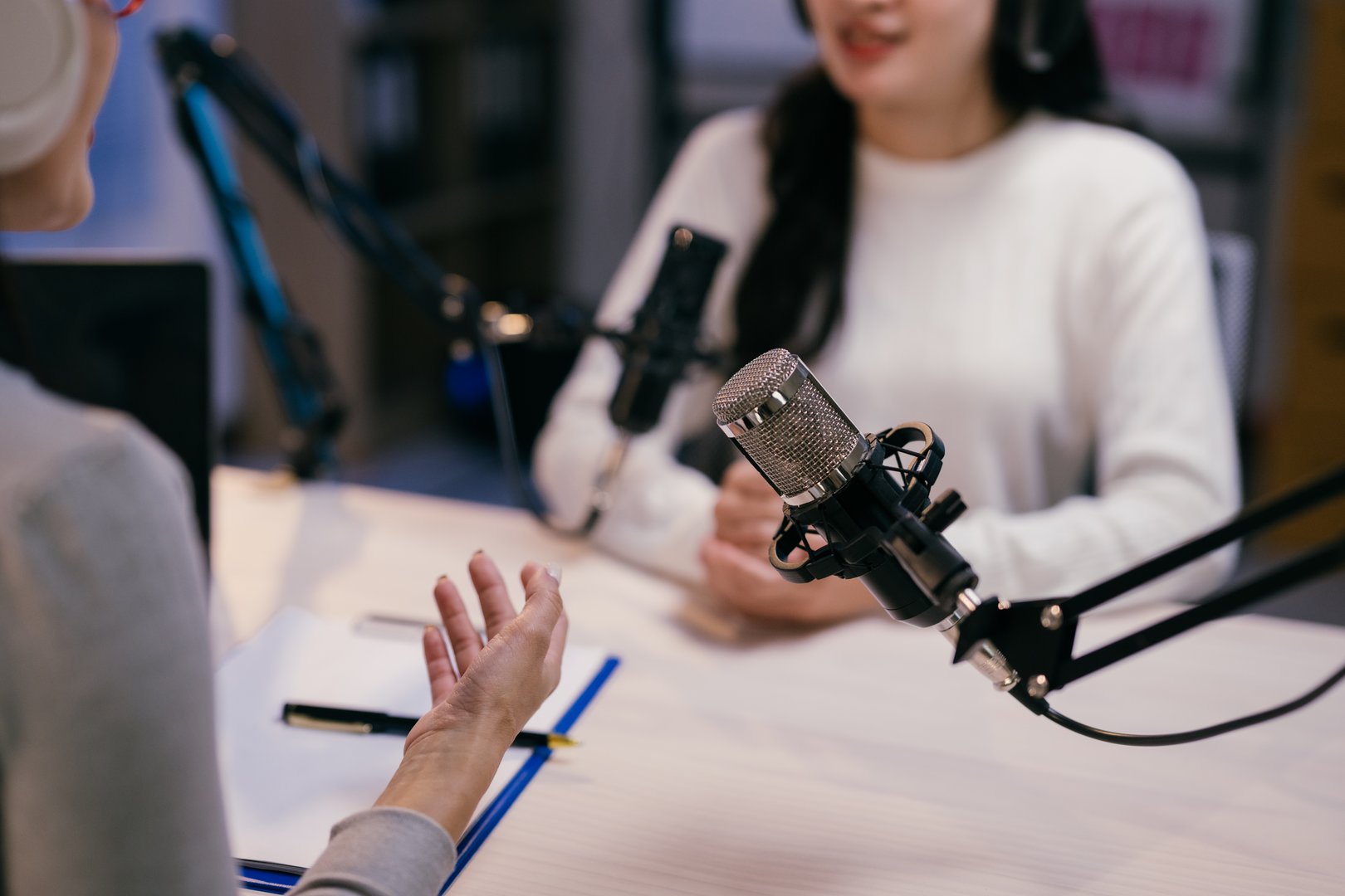 Two young female podcasters are recording a podcast episode, engaging in a lively discussion and sharing their insights with their audience