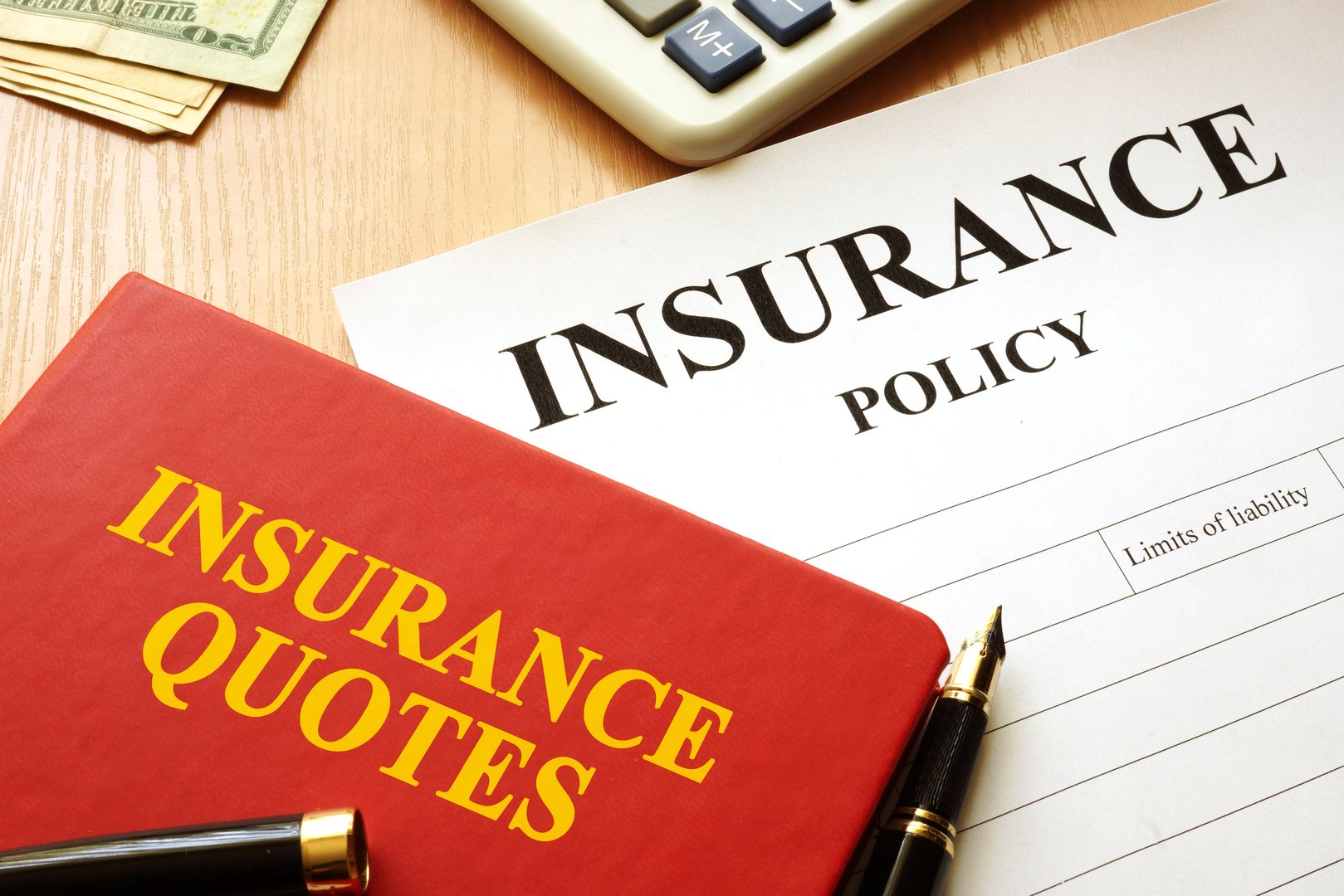 Insurance quotes book and policy on a desk.