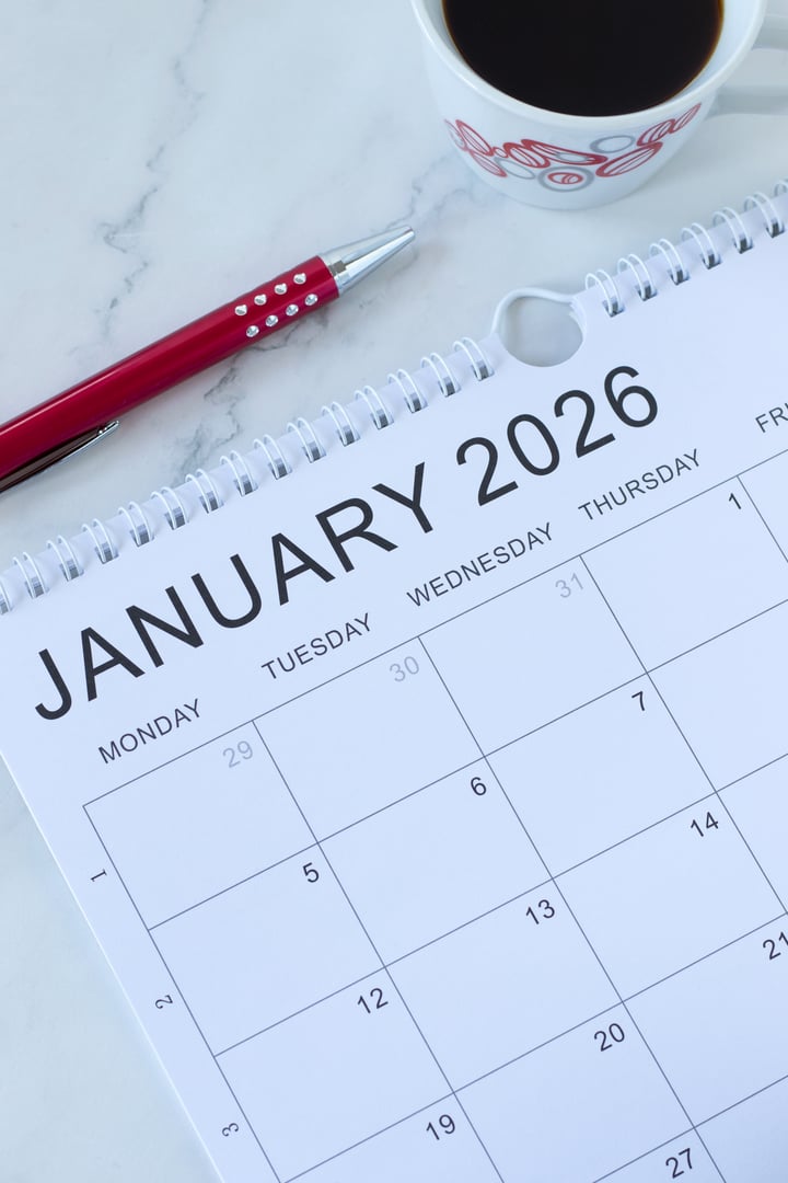 January 2026 new year calendar with pen and coffee cup on a desk. Top view. Annual goals, budget, planning, aspirations, business concept.