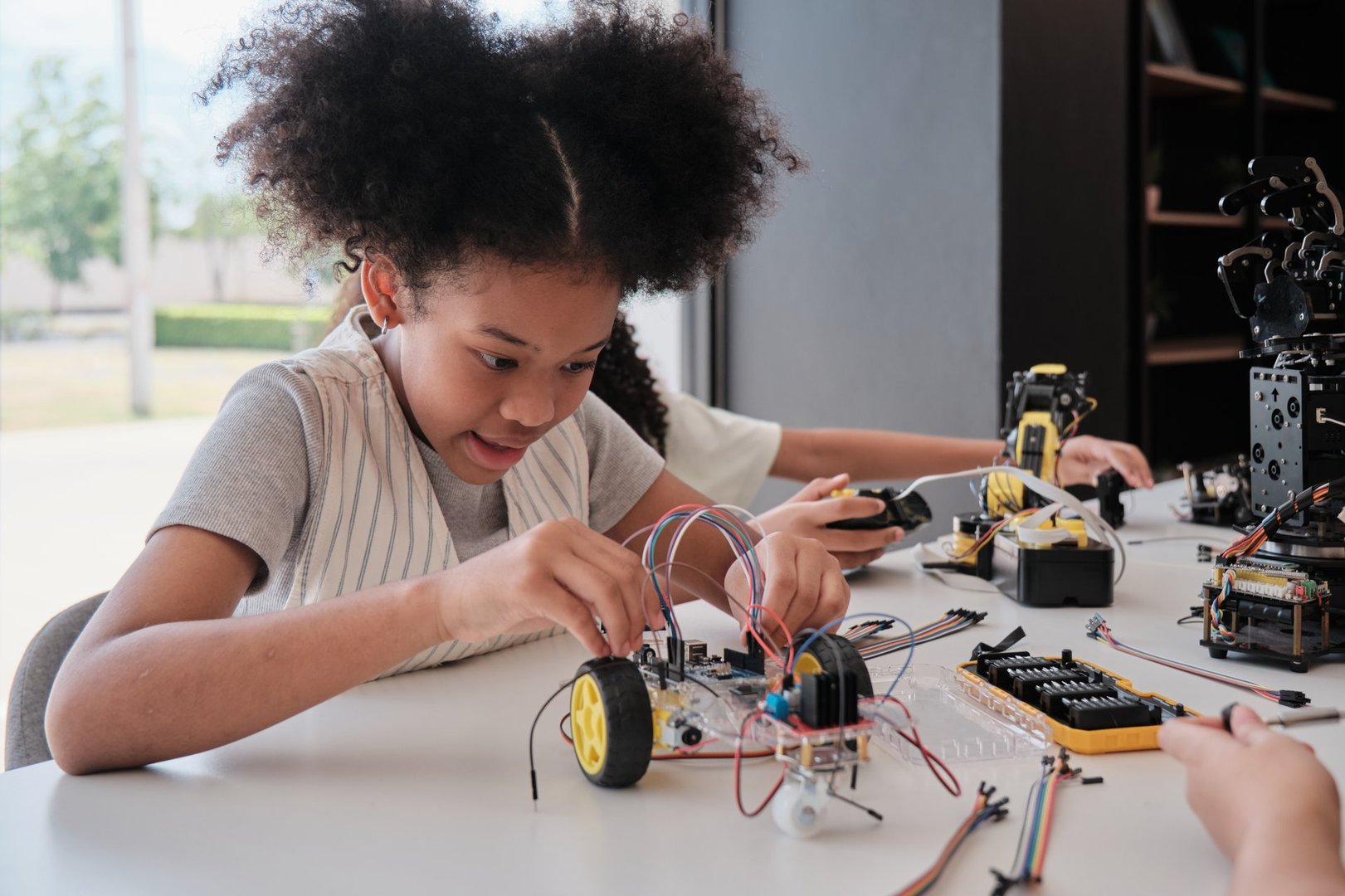 Black student girl robotic mechanical design and electric experiments, learning class in science engineering classroom course, creativity, technology knowledge for kids education of elementary school.