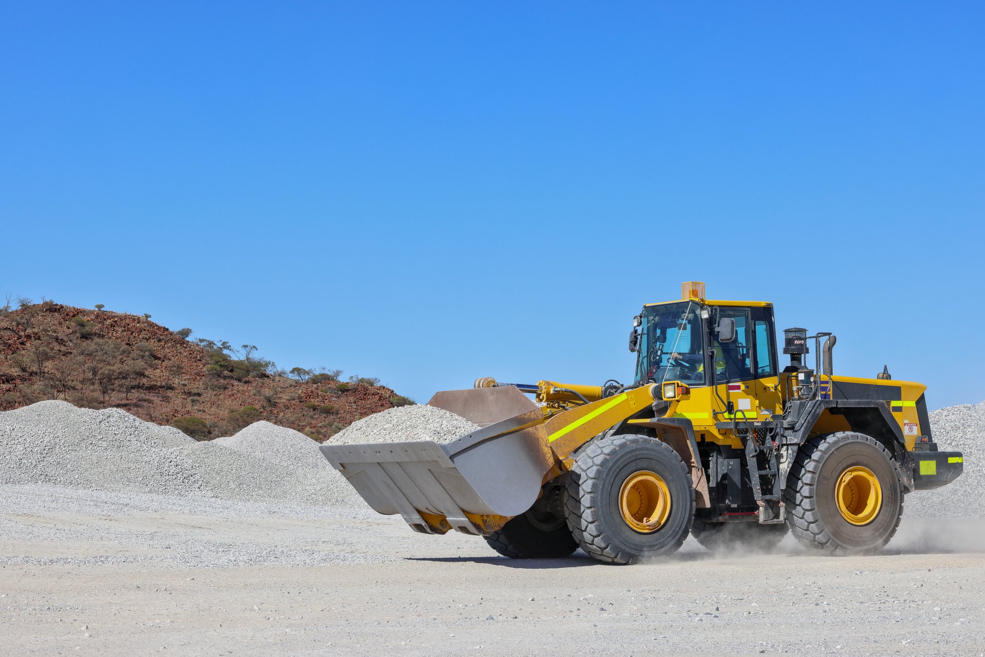 Front-end loader (bucket loader, payloader, high lift, scoop, shovel dozer, skid-steer, skip loader, tractor loader or wheel loader) moving ore at a mine in Outback Western Australia