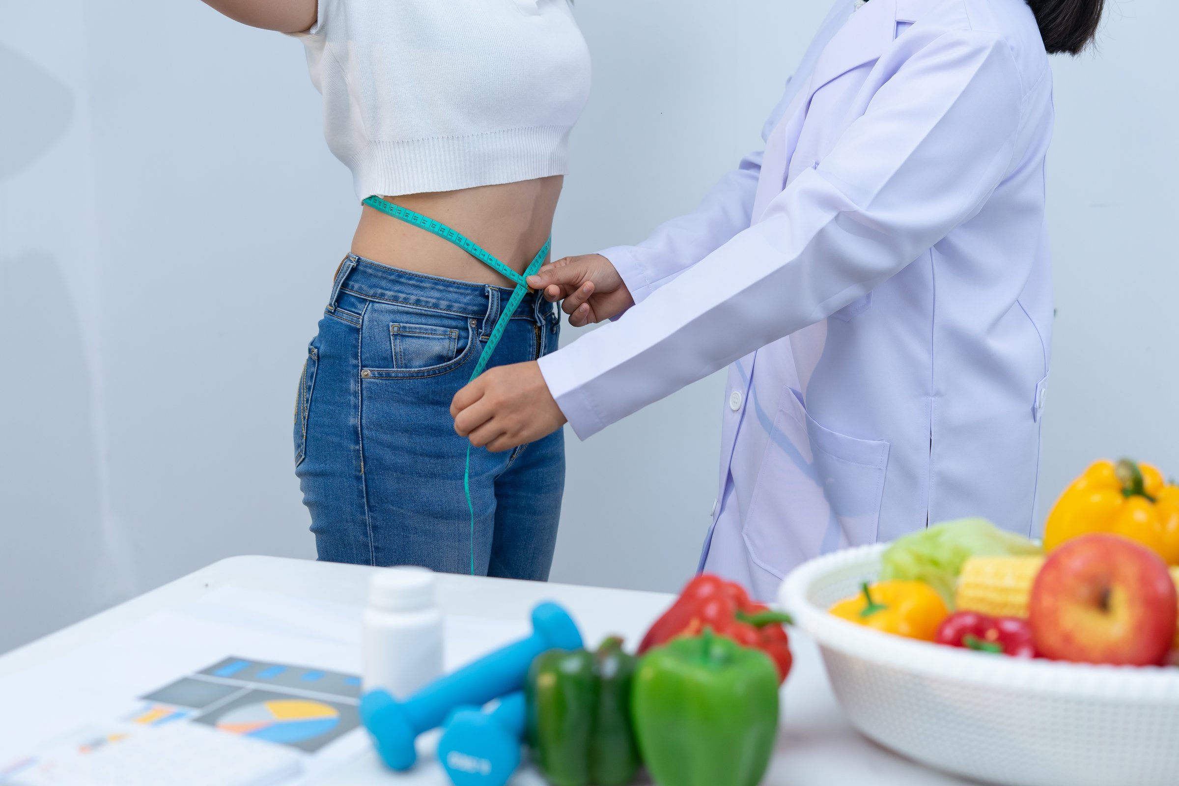 A nutritionist measures woman waist in health consultation