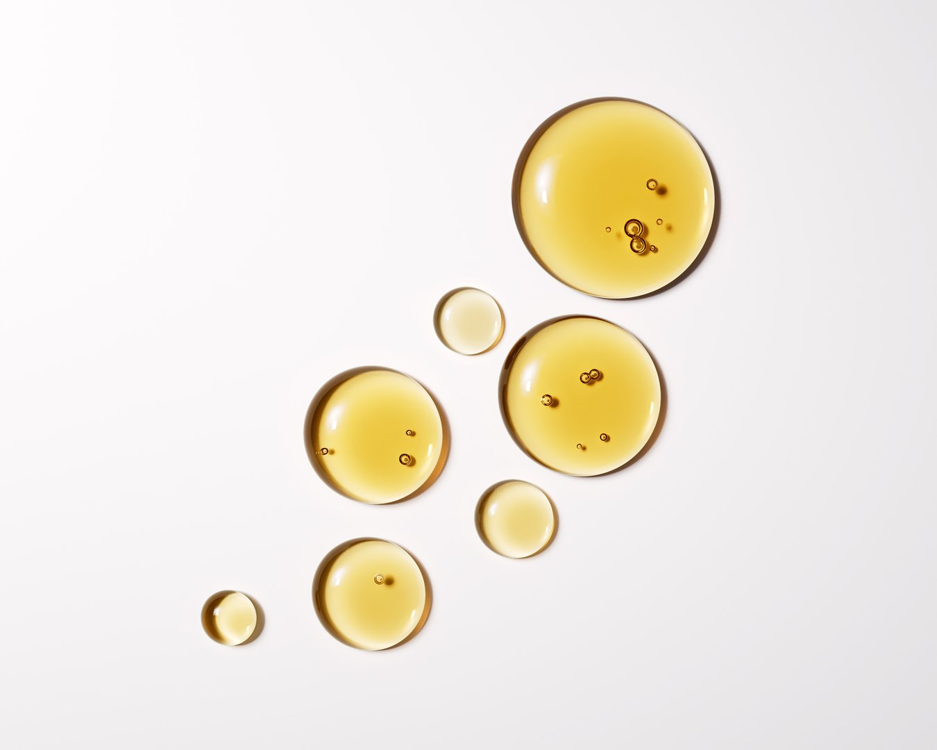 High-quality close-up of golden liquid oil drops isolated on white, 3d rendering face serum cosmetic beauty product design High-quality close-up of golden liquid oil drops isolated on white, 3d rendering face serum cosmetic beauty product design elements