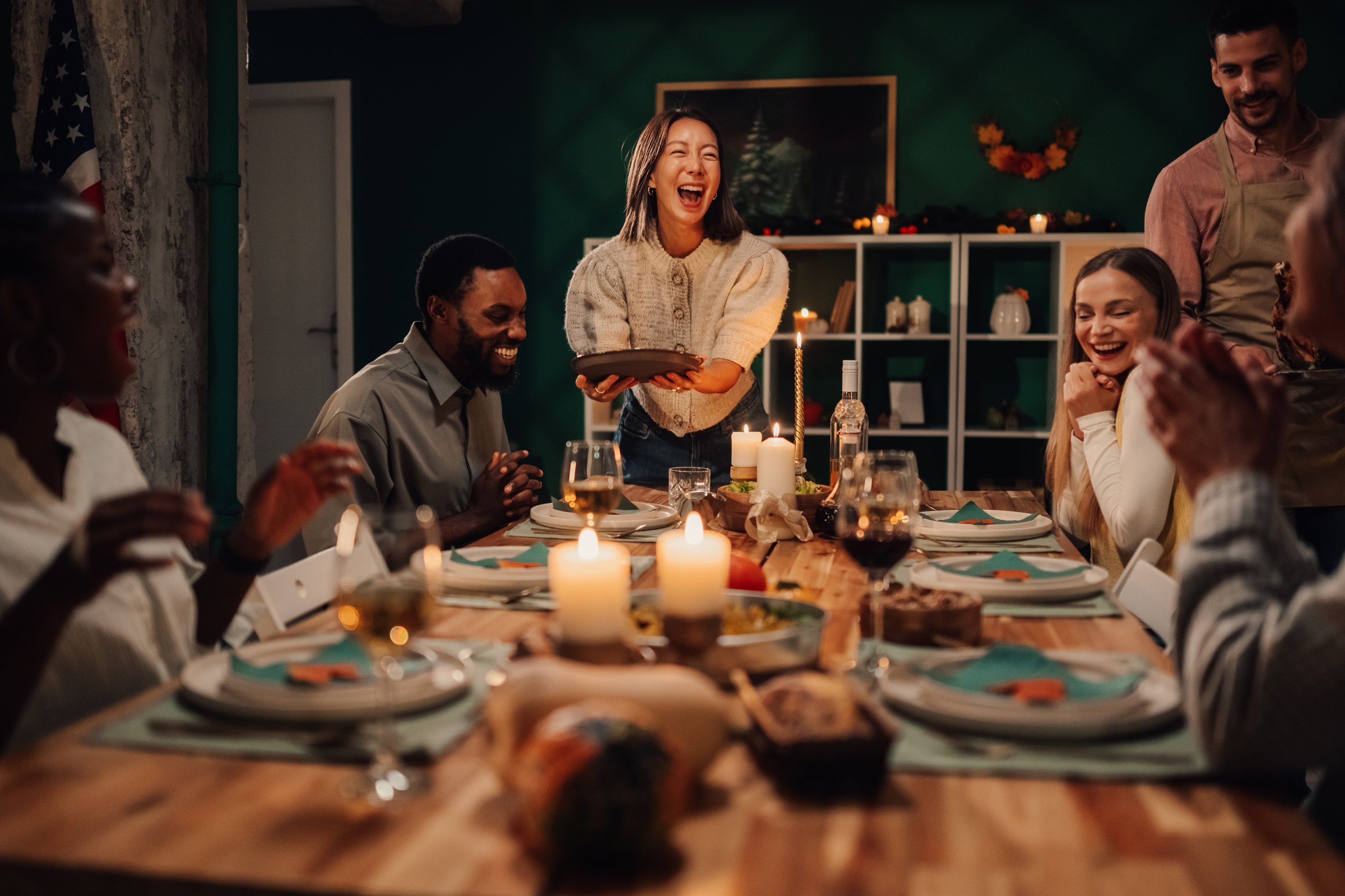 Happy multi-ethnic friends and family are laughing and enjoying a festive meal together at home