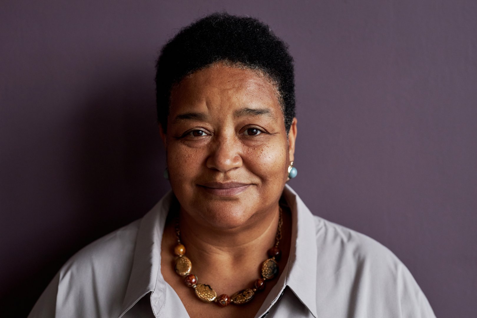 Front view portrait of senior black woman smiling at camera against purple background