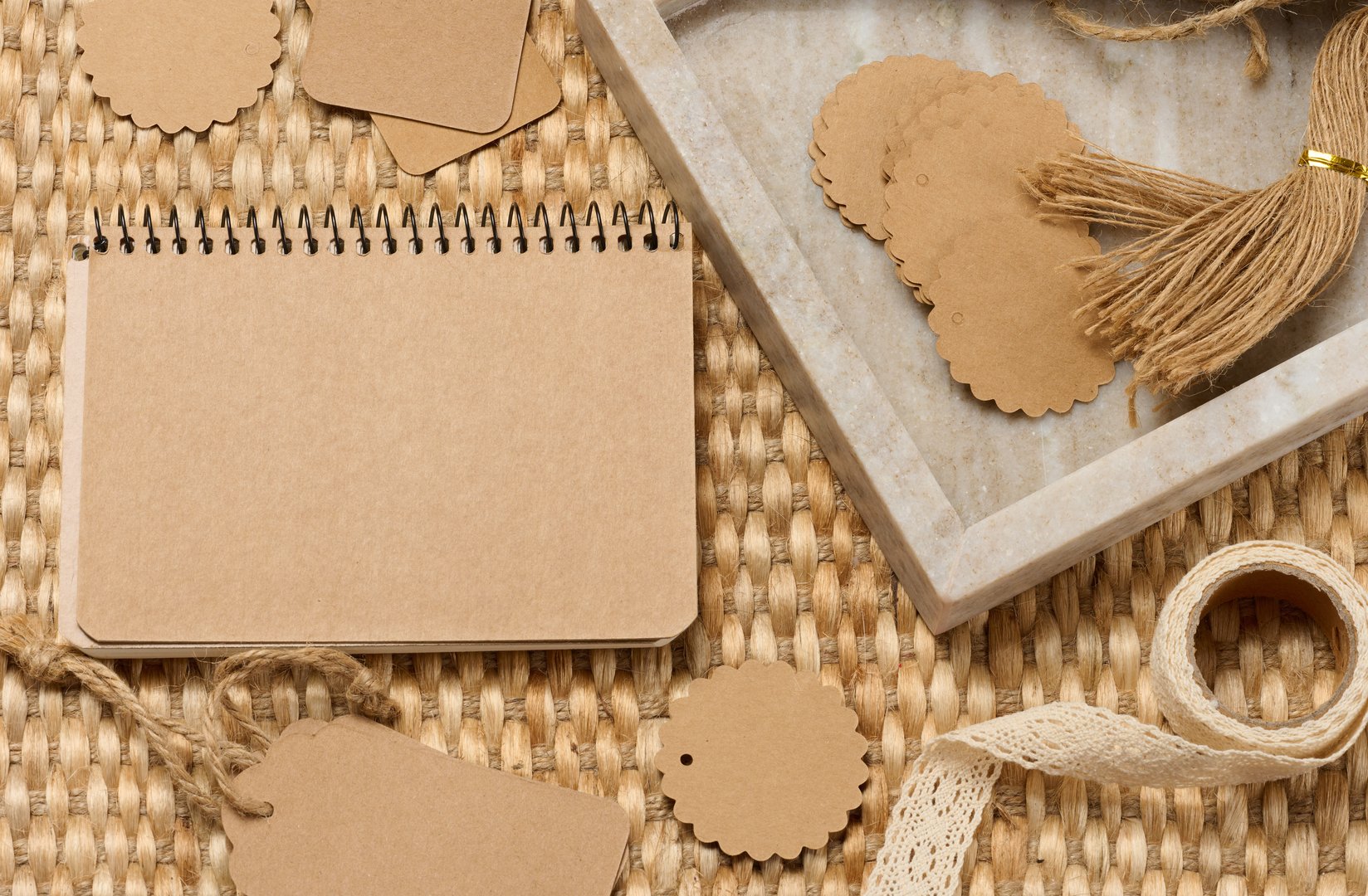 Blank notepad and various craft supplies made of recycled paper and twine on a woven mat. DIY, handcrafted goods, eco-friendly